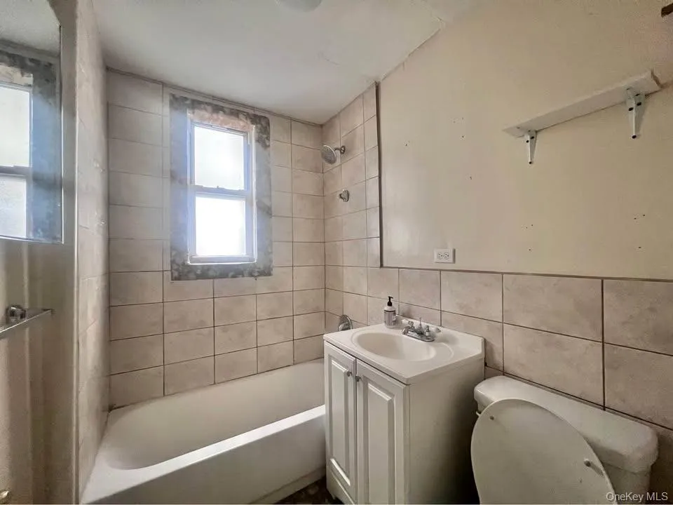 Bathroom with tub / shower combination, vanity, and tile walls Bathroom with tub / shower combination, vanity, and tile walls