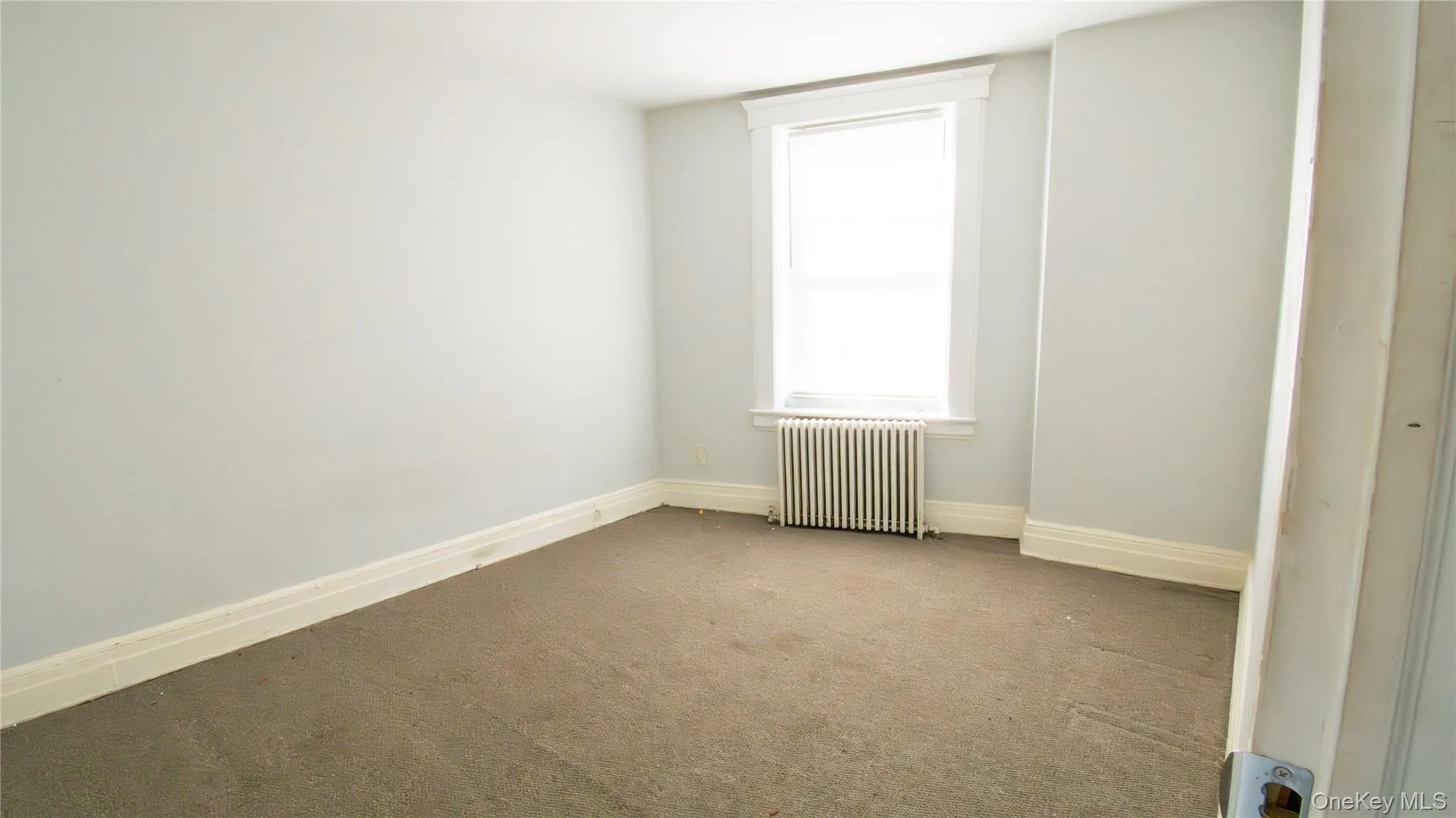 Carpeted spare room featuring radiator and baseboards Carpeted spare room featuring radiator and baseboards