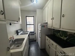 Kitchen with range with gas cooktop, white cabinetry, dark wood-type flooring, and light countertops Kitchen with range with gas cooktop, white cabinetry, dark wood-type flooring, and light countertops