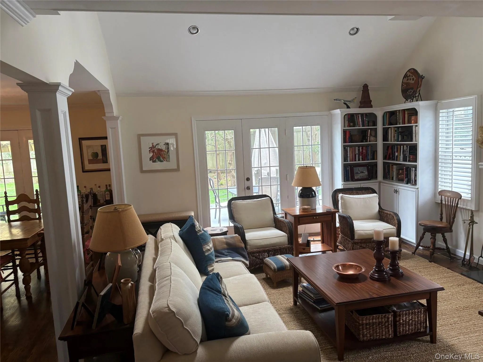 Living room featuring plenty of natural light, wood finished floors, French doors, lofted ceiling, and decorative columns Living room featuring plenty of natural light, wood finished floors, French doors, lofted ceiling, and decorative columns