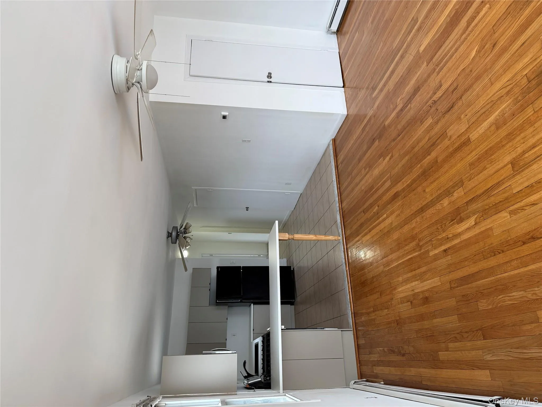 Unfurnished living room featuring ceiling fan, light wood-style floors, and baseboard heating Unfurnished living room featuring ceiling fan, light wood-style floors, and baseboard heating