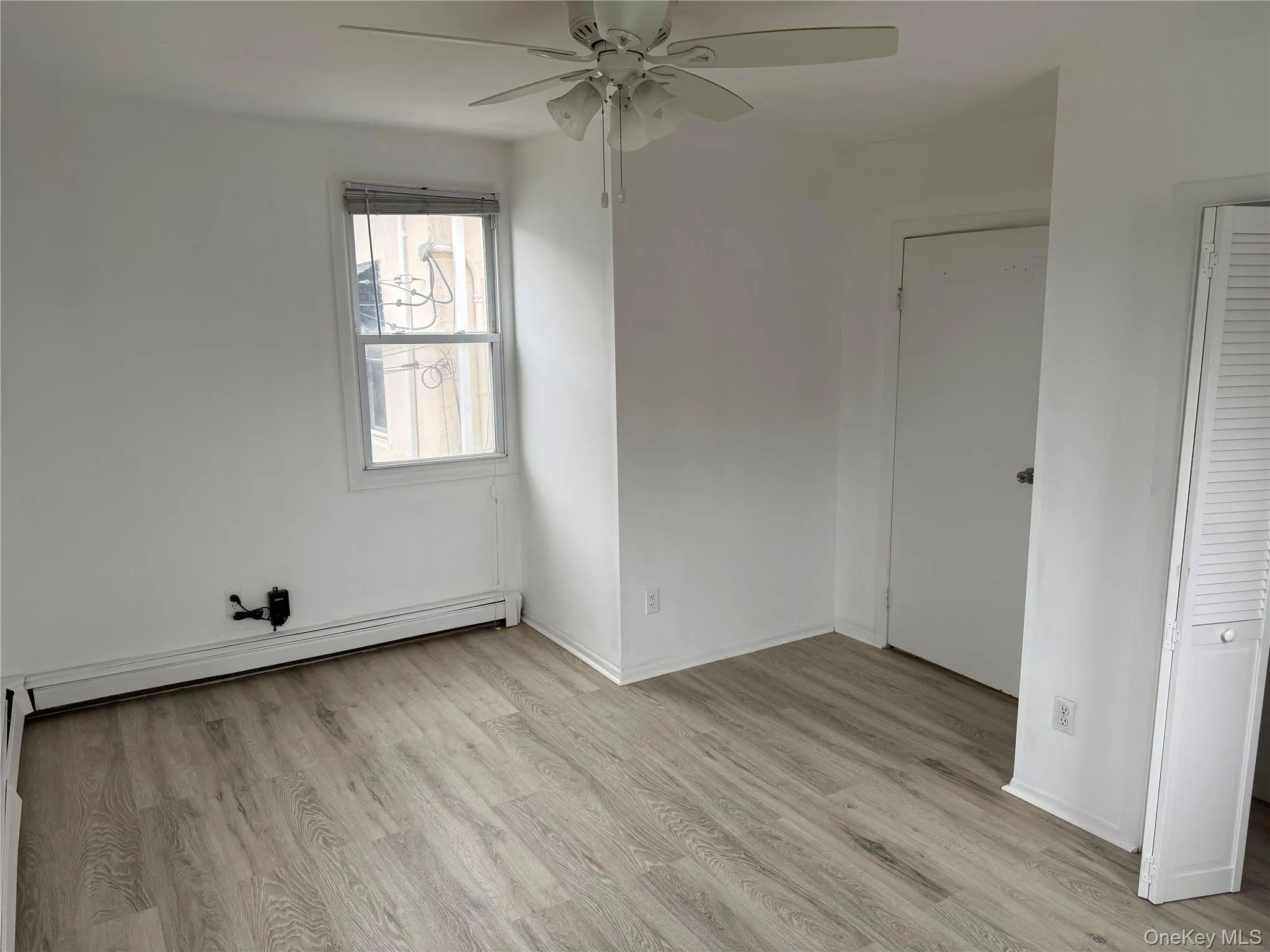 Unfurnished bedroom featuring light wood finished floors, baseboard heating, and ceiling fan Unfurnished bedroom featuring light wood finished floors, baseboard heating, and ceiling fan