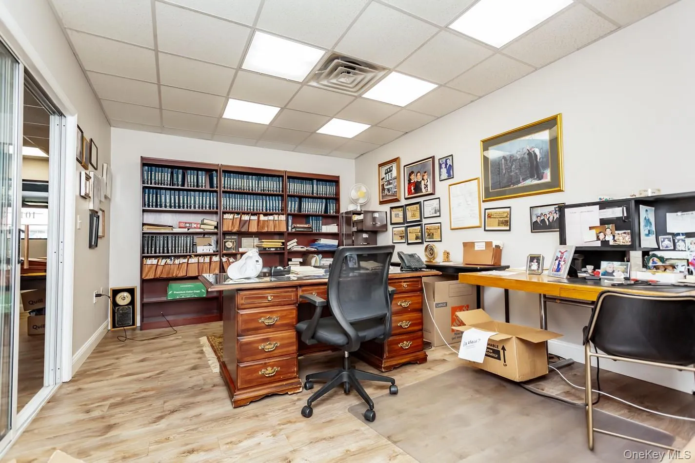 Office space with a drop ceiling, light wood-type flooring, and built in desk Office space with a drop ceiling, light wood-type flooring, and built in desk