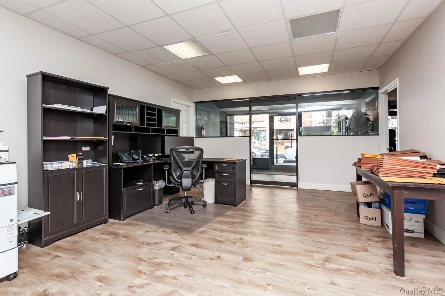 Office featuring a paneled ceiling, light wood-type flooring, and built in desk Office featuring a paneled ceiling, light wood-type flooring, and built in desk