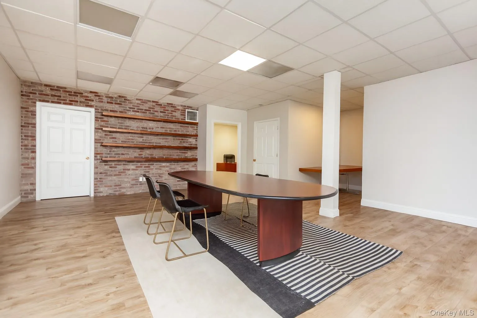 (Digitally Decluttered) Home office featuring brick wall, light wood-style flooring, and a paneled ceiling (Digitally Decluttered) Home office featuring brick wall, light wood-style flooring, and a paneled ceiling