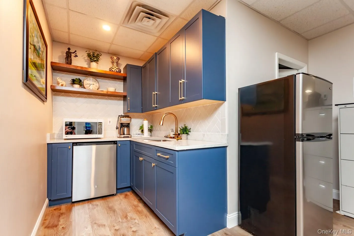 Kitchen with a paneled ceiling, freestanding refrigerator, tasteful backsplash, open shelves, and stainless steel refrigerator Kitchen with a paneled ceiling, freestanding refrigerator, tasteful backsplash, open shelves, and stainless steel refrigerator