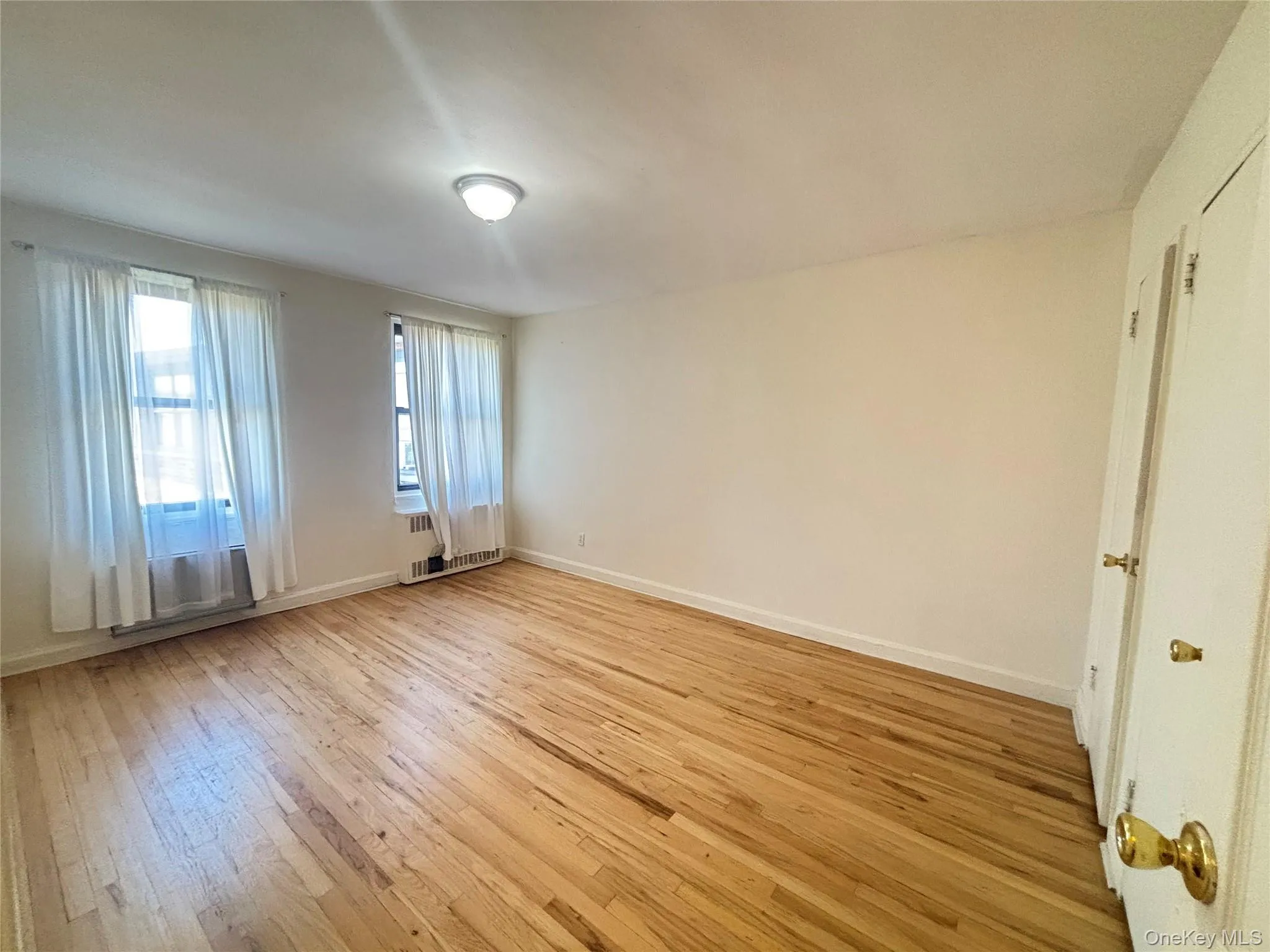 Spare room featuring light wood-type flooring and radiator heating unit Spare room featuring light wood-type flooring and radiator heating unit