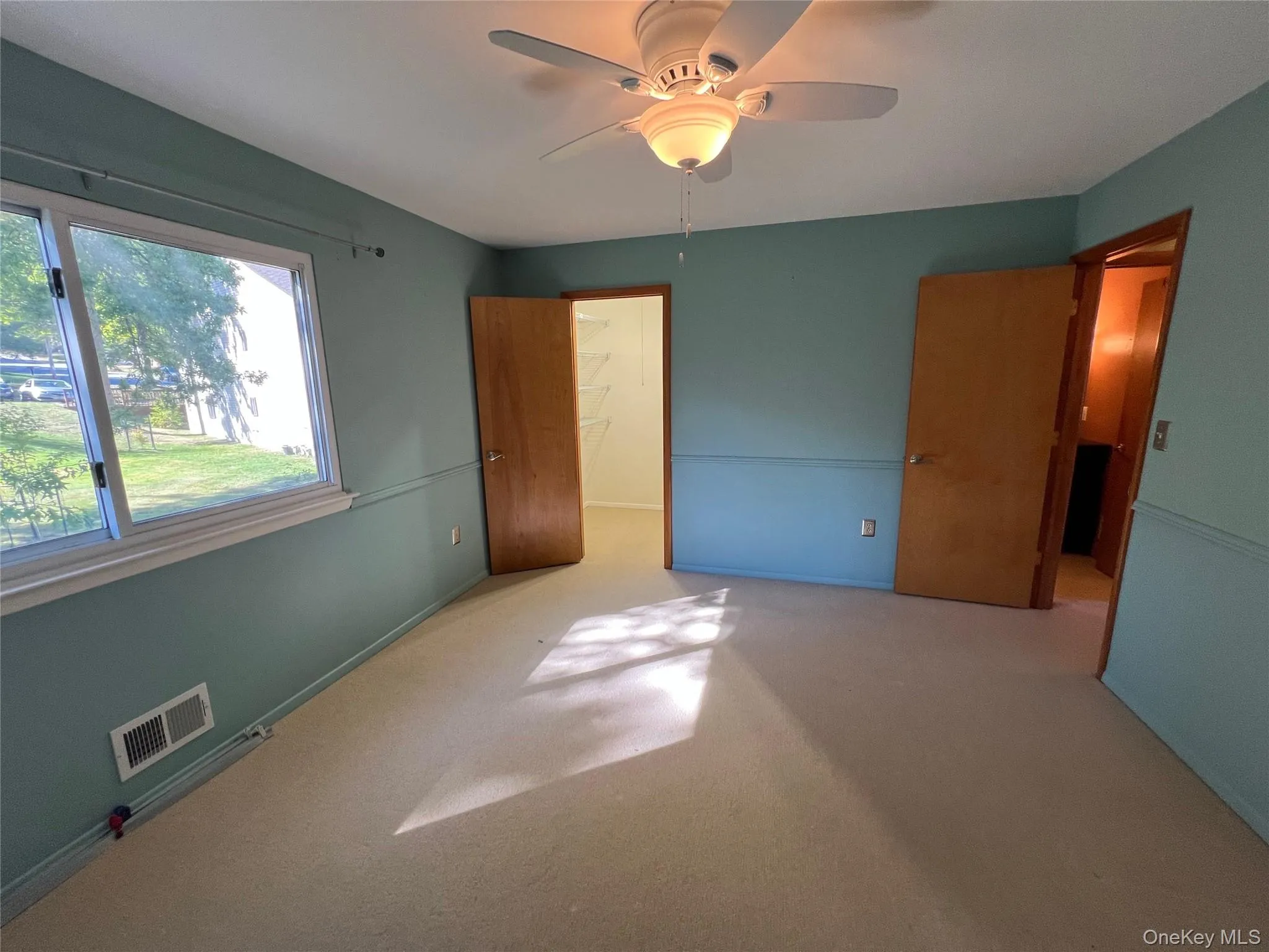 bedroom featuring carpet, a ceiling fan, and a spacious closet bedroom featuring carpet, a ceiling fan, and a spacious closet