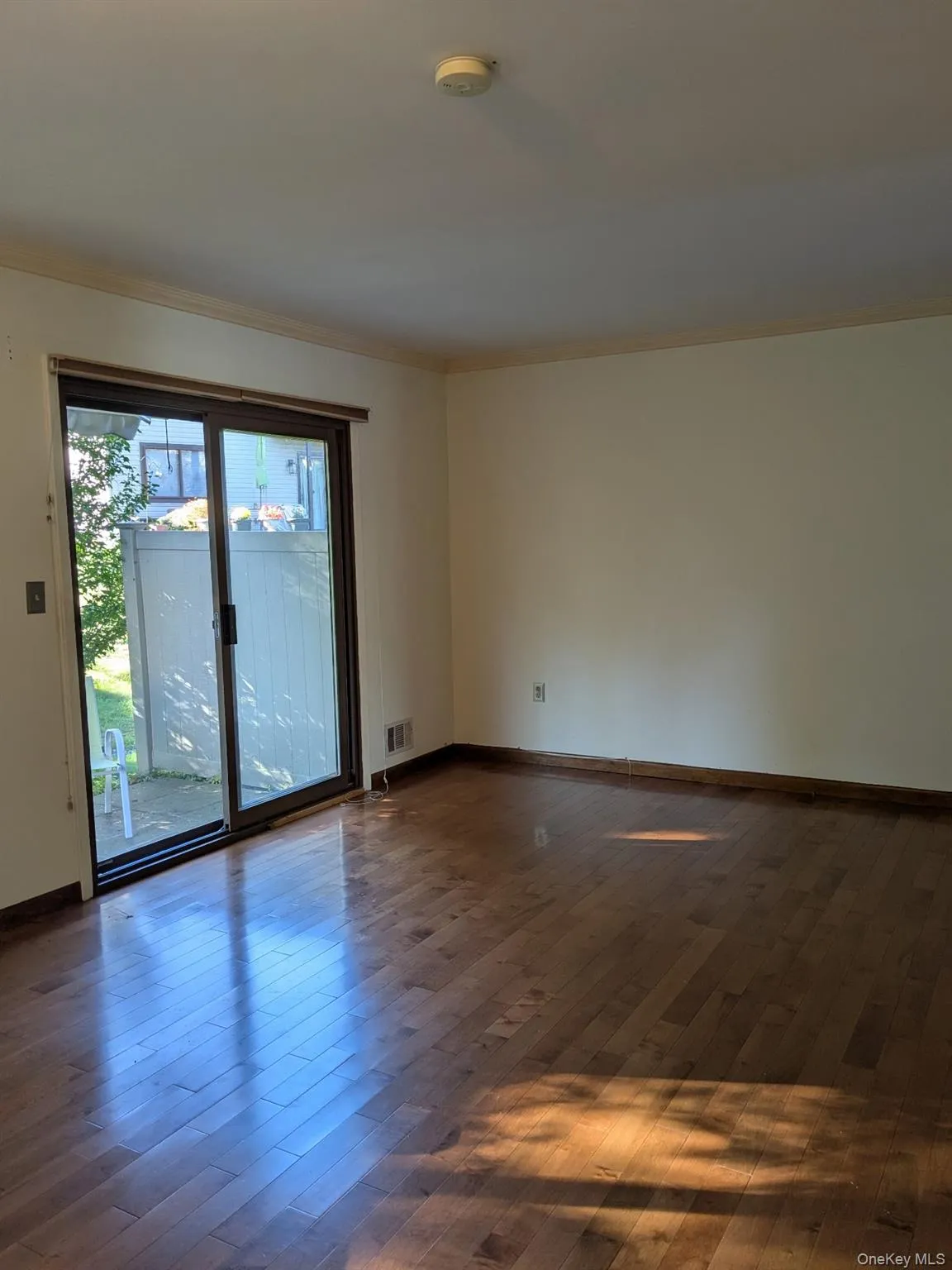 Living room with hardwood / wood-style flooring and crown molding, entrance to patio Living room with hardwood / wood-style flooring and crown molding, entrance to patio