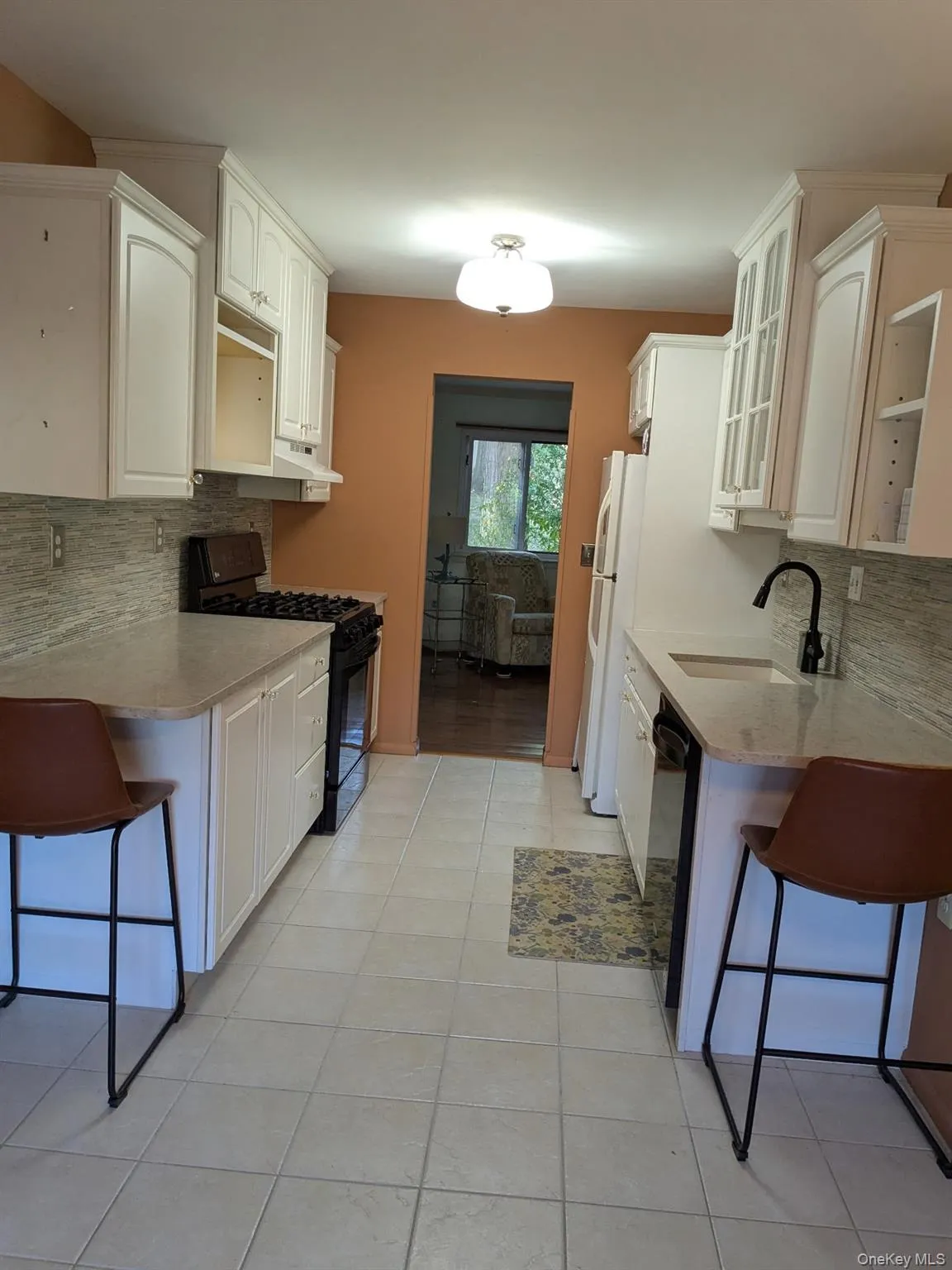 Kitchen with backsplash, a breakfast bar area, black appliances, and glass insert cabinets Kitchen with backsplash, a breakfast bar area, black appliances, and glass insert cabinets