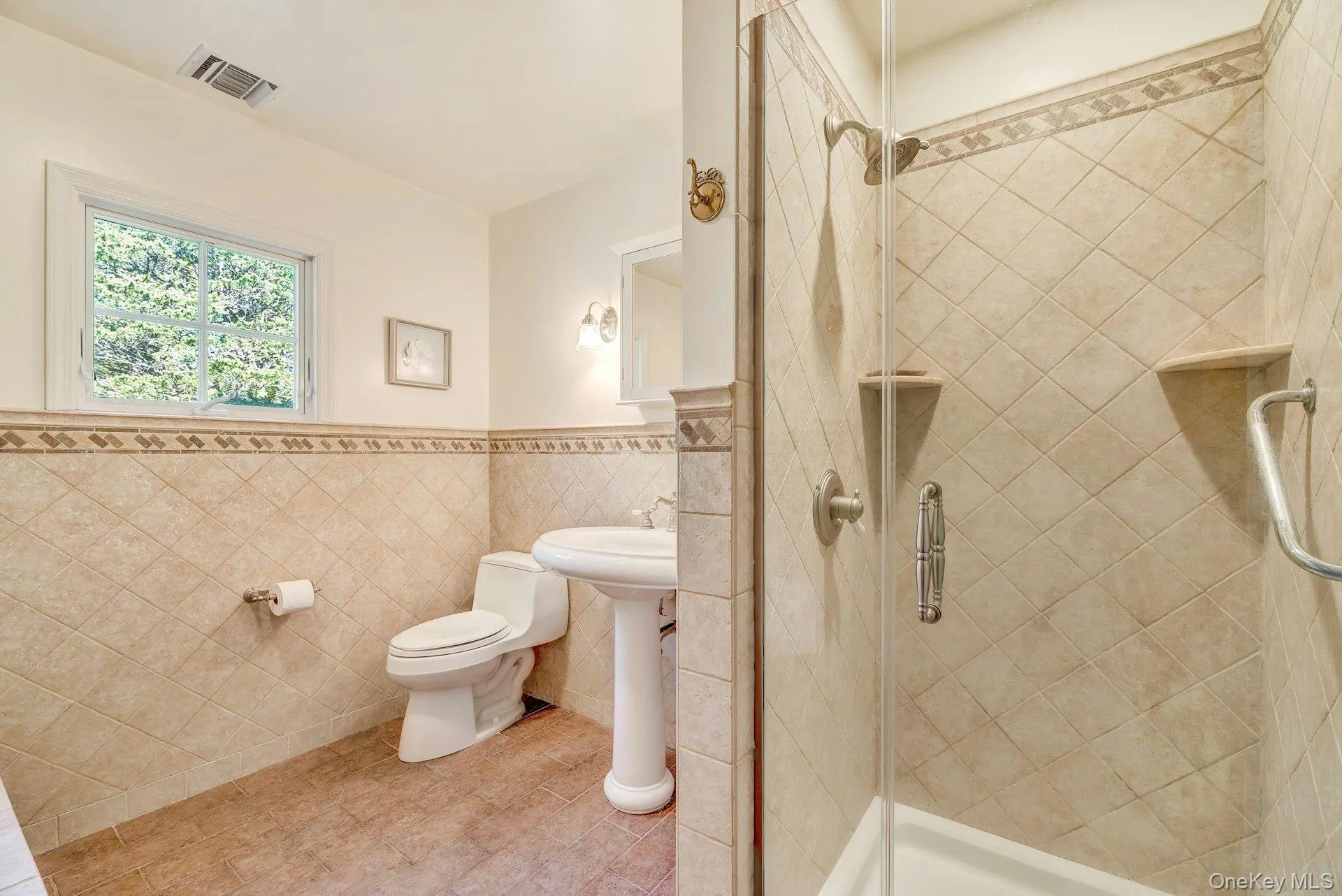 Full bath with a shower stall, tile walls, a wainscoted wall, and tile patterned floors Full bath with a shower stall, tile walls, a wainscoted wall, and tile patterned floors