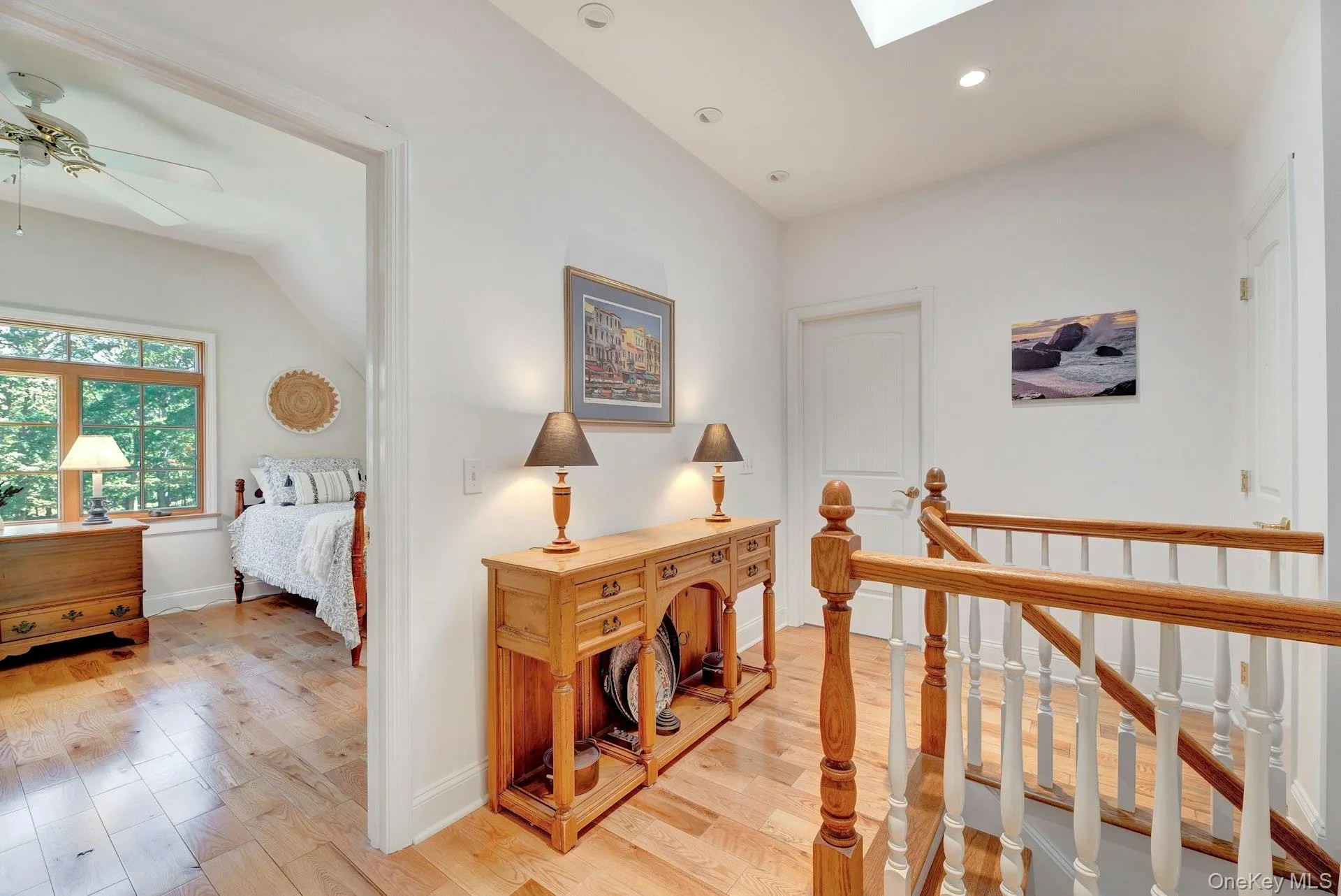 Corridor featuring light wood-style flooring, an upstairs landing, a skylight, recessed lighting, and lofted ceiling Corridor featuring light wood-style flooring, an upstairs landing, a skylight, recessed lighting, and lofted ceiling