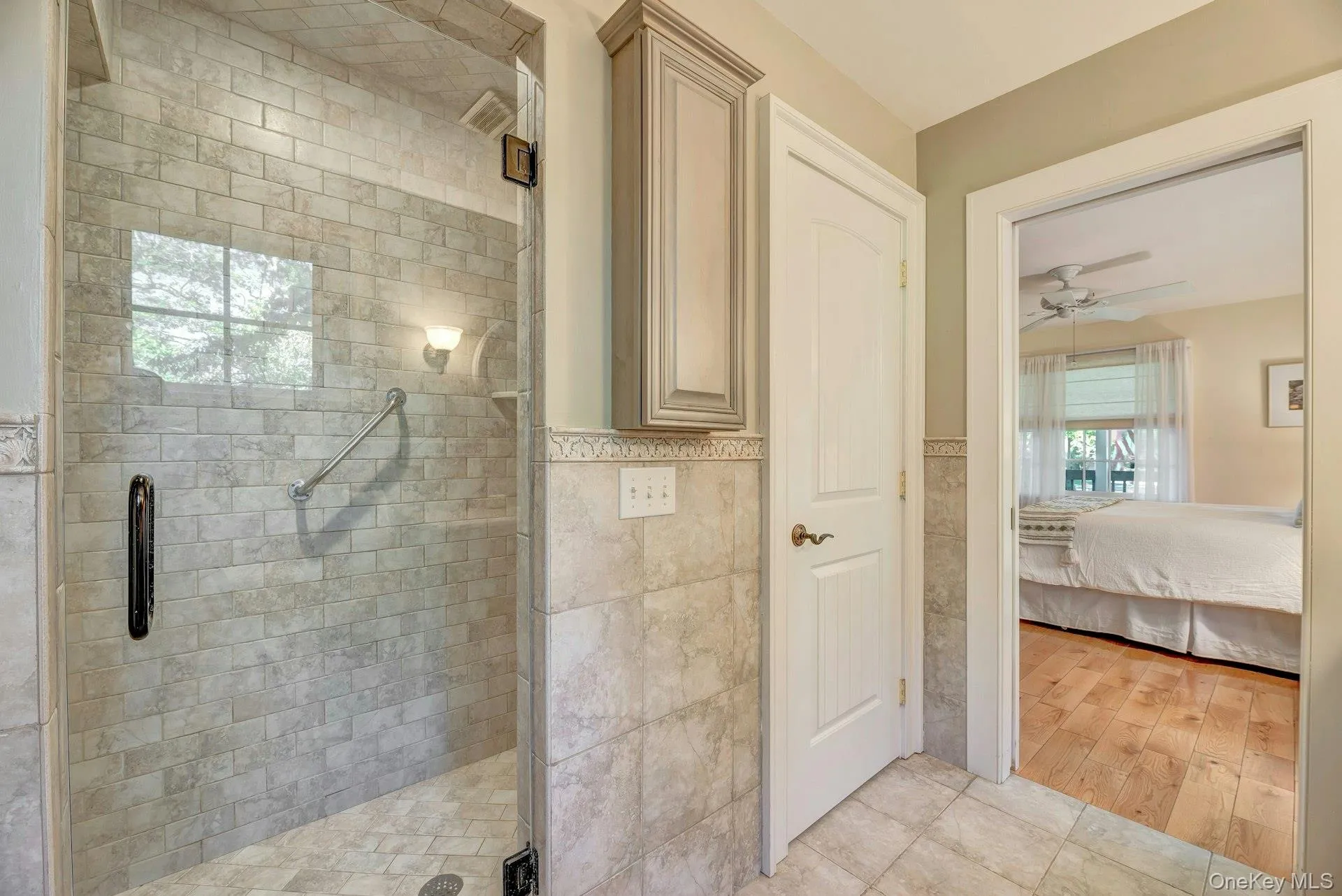 Full bath featuring a stall shower, ensuite bath, tile walls, ceiling fan, and a wainscoted wall Full bath featuring a stall shower, ensuite bath, tile walls, ceiling fan, and a wainscoted wall