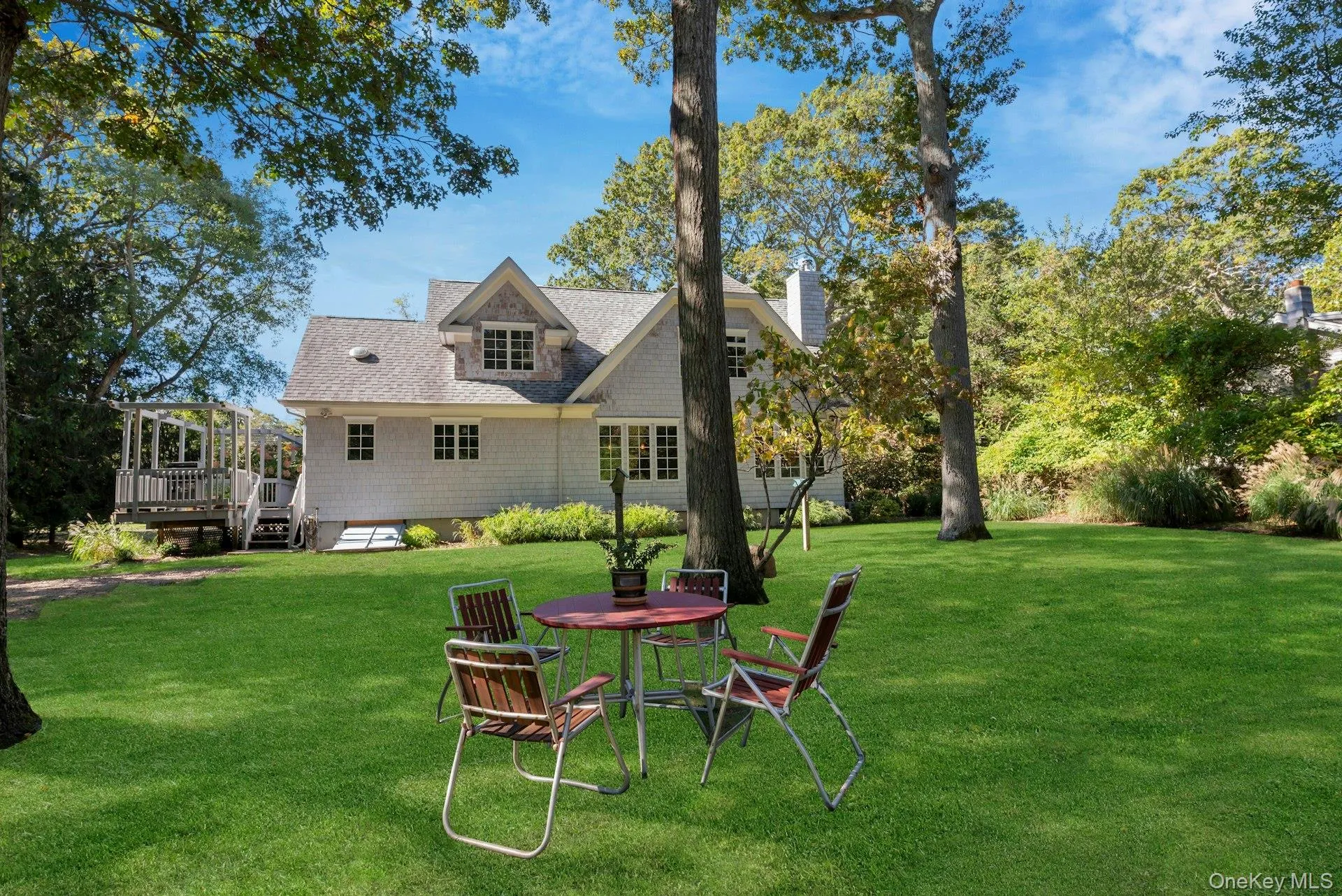 Back of property with a yard, a shingled roof, a deck, and a chimney Back of property with a yard, a shingled roof, a deck, and a chimney