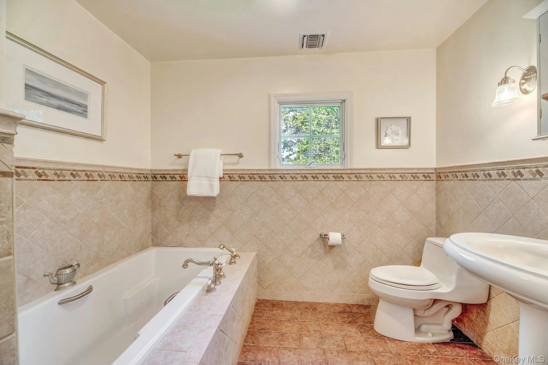 Full bathroom with a garden tub, light tile patterned floors, a wainscoted wall, and tile walls Full bathroom with a garden tub, light tile patterned floors, a wainscoted wall, and tile walls