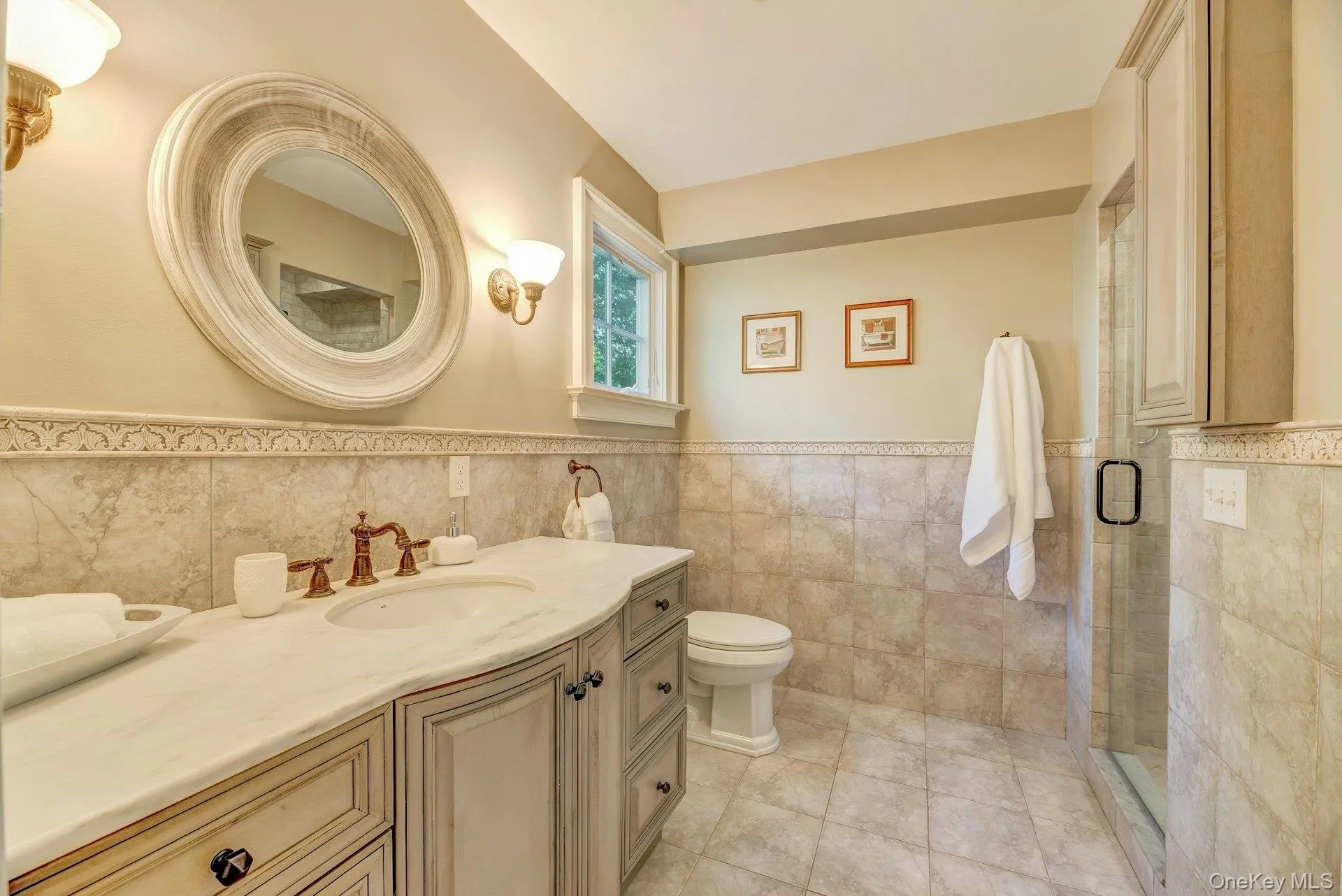 Bathroom with vanity, tile walls, a wainscoted wall, a stall shower, and light tile patterned floors Bathroom with vanity, tile walls, a wainscoted wall, a stall shower, and light tile patterned floors