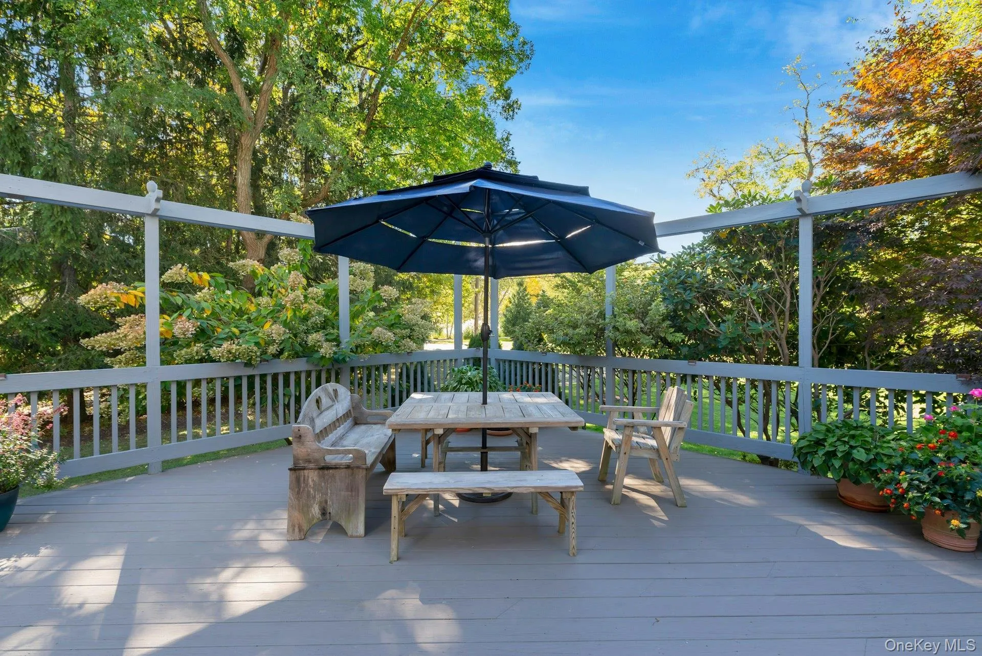 Wooden deck with outdoor dining space and view of scattered trees Wooden deck with outdoor dining space and view of scattered trees