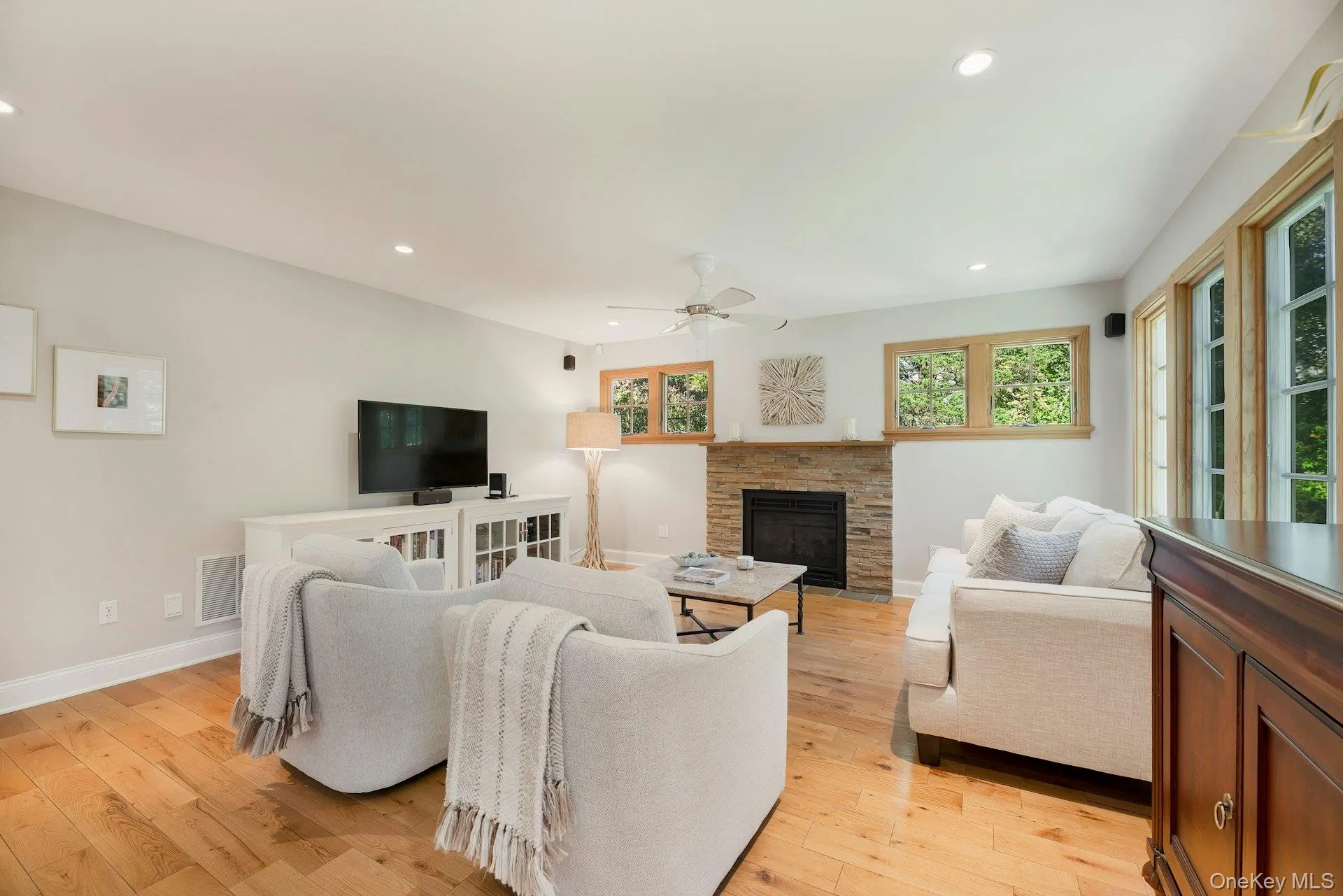 Living area featuring light wood finished floors, a fireplace, recessed lighting, and a ceiling fan Living area featuring light wood finished floors, a fireplace, recessed lighting, and a ceiling fan