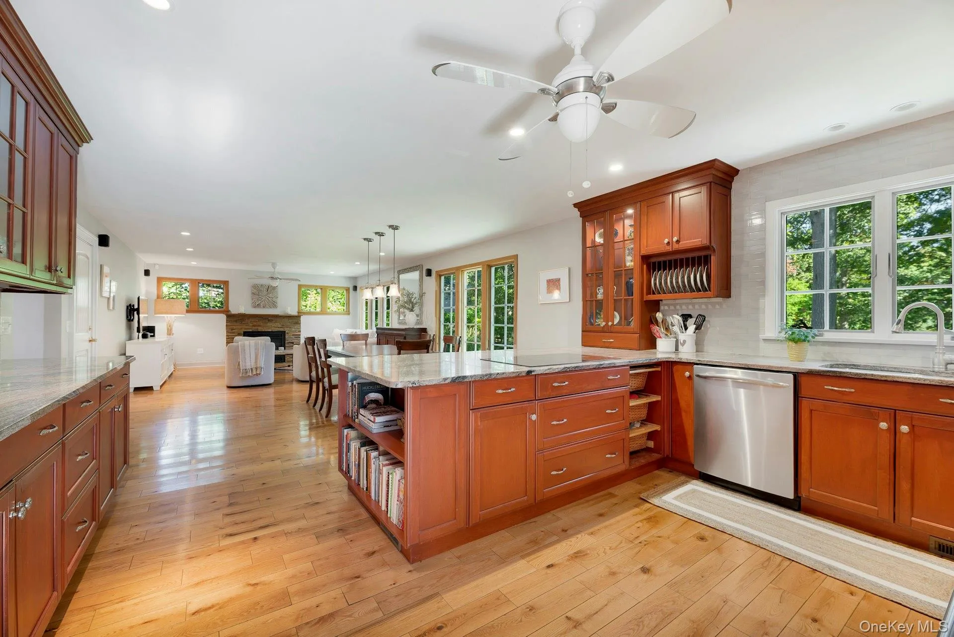 Kitchen with glass insert cabinets, open shelves, light stone counters, open floor plan, and recessed lighting Kitchen with glass insert cabinets, open shelves, light stone counters, open floor plan, and recessed lighting