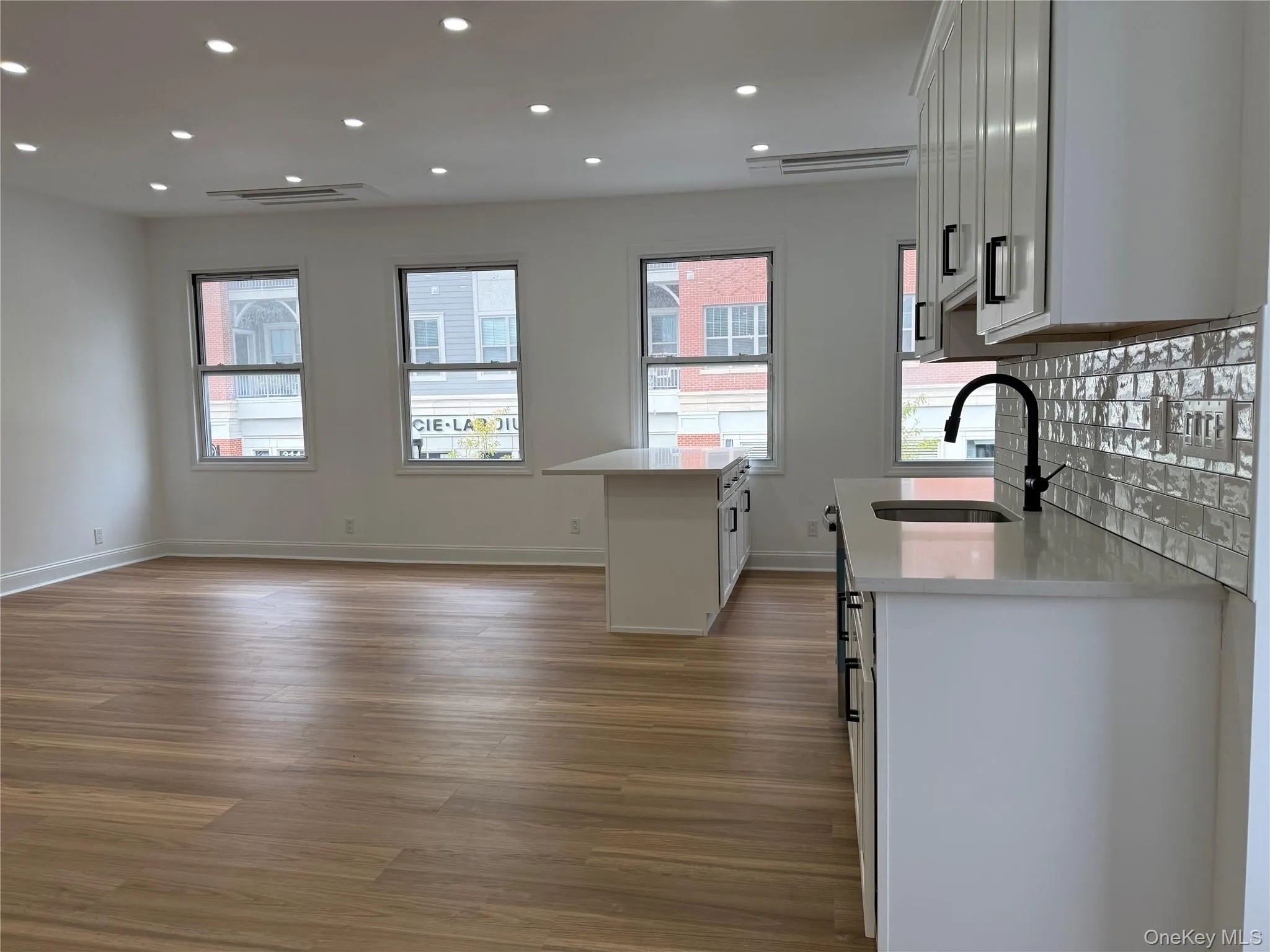 Kitchen with light stone counters, light wood finished floors, healthy amount of natural light, white cabinets, and recessed lighting Kitchen with light stone counters, light wood finished floors, healthy amount of natural light, white cabinets, and recessed lighting