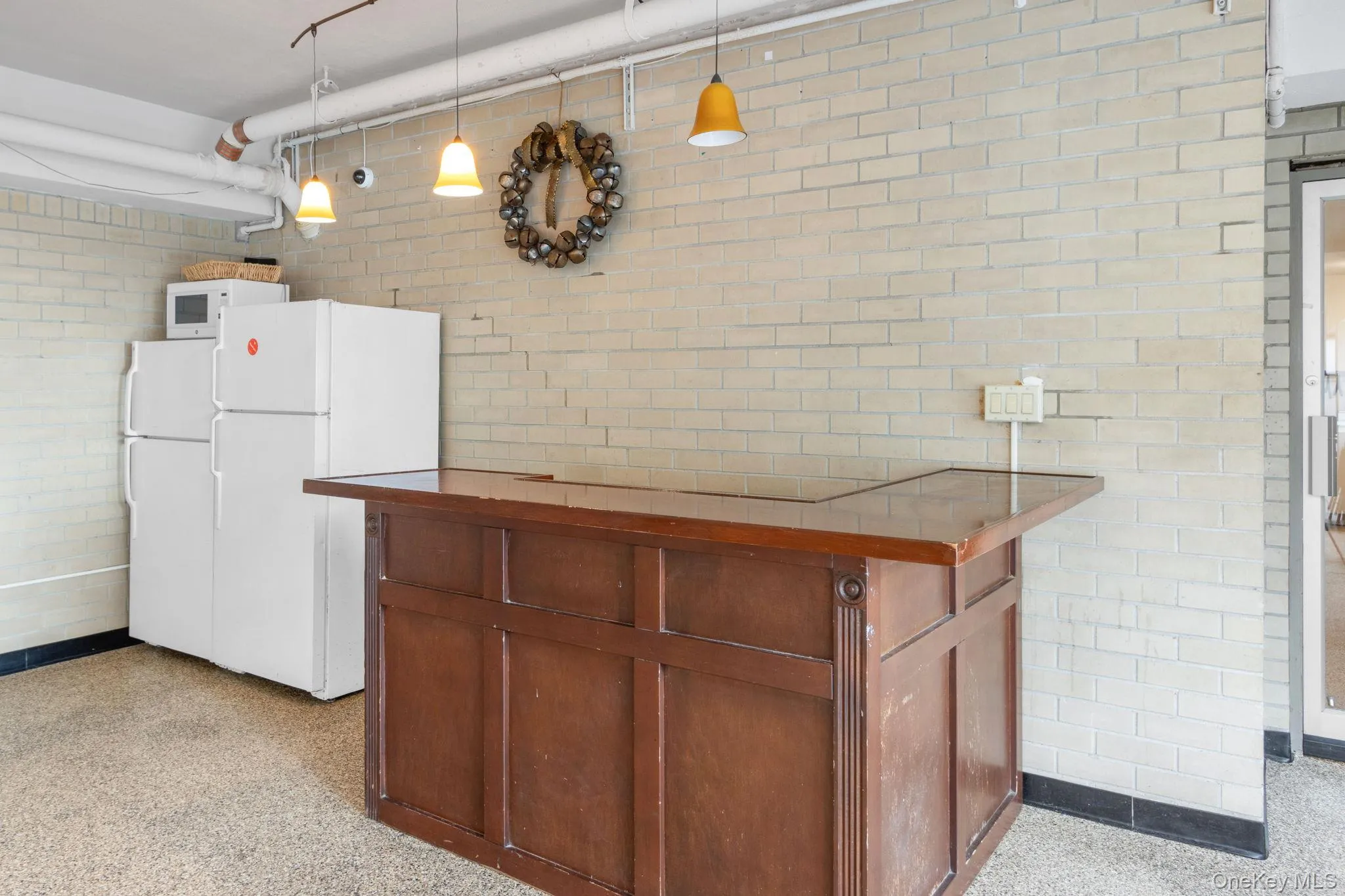 Kitchen with white appliances, decorative light fixtures, dark speckled floor, brick wall, and wood counters Kitchen with white appliances, decorative light fixtures, dark speckled floor, brick wall, and wood counters