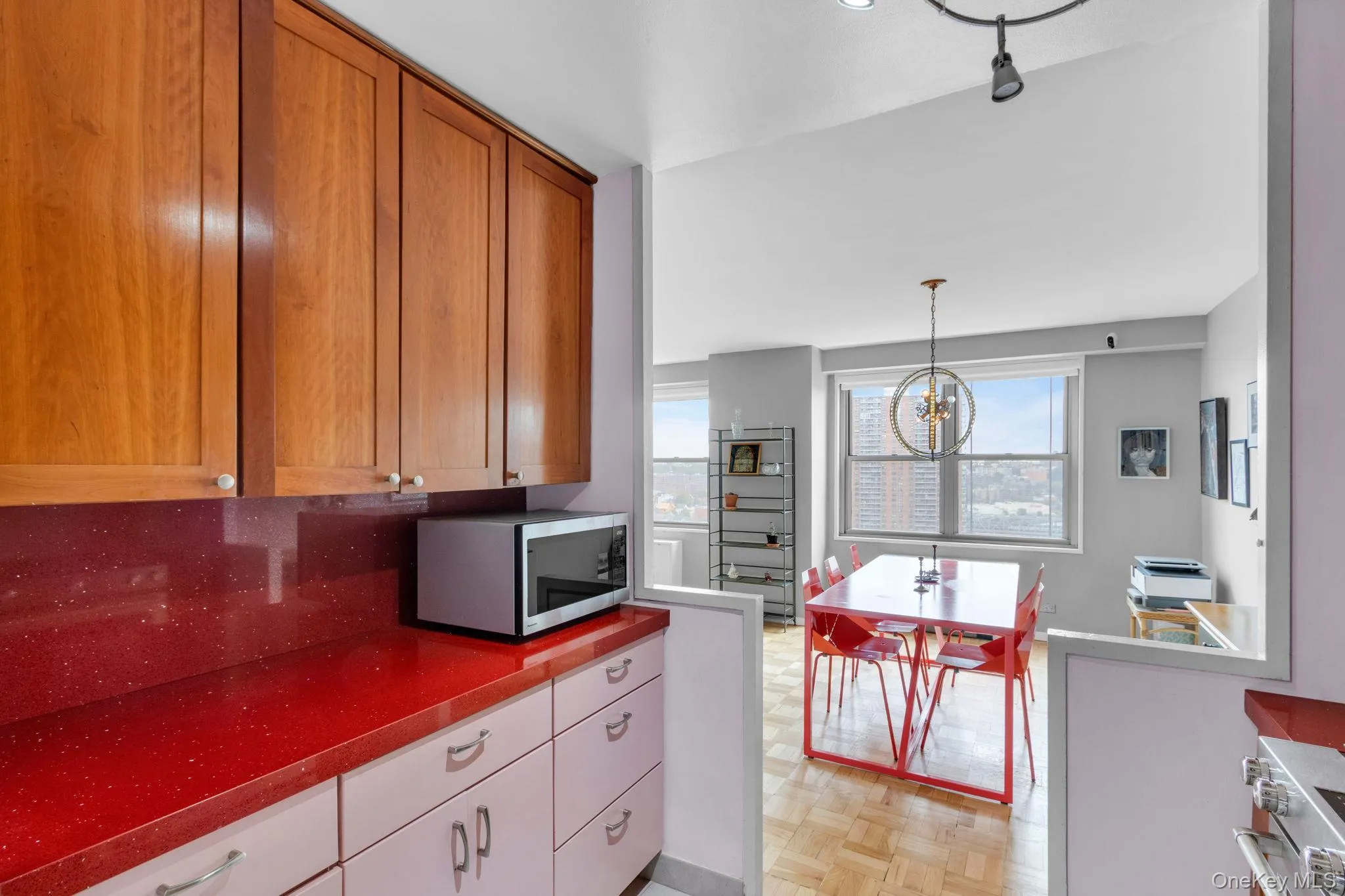 Kitchen with hanging light fixtures, appliances with stainless steel finishes, a chandelier, and brown cabinetry Kitchen with hanging light fixtures, appliances with stainless steel finishes, a chandelier, and brown cabinetry