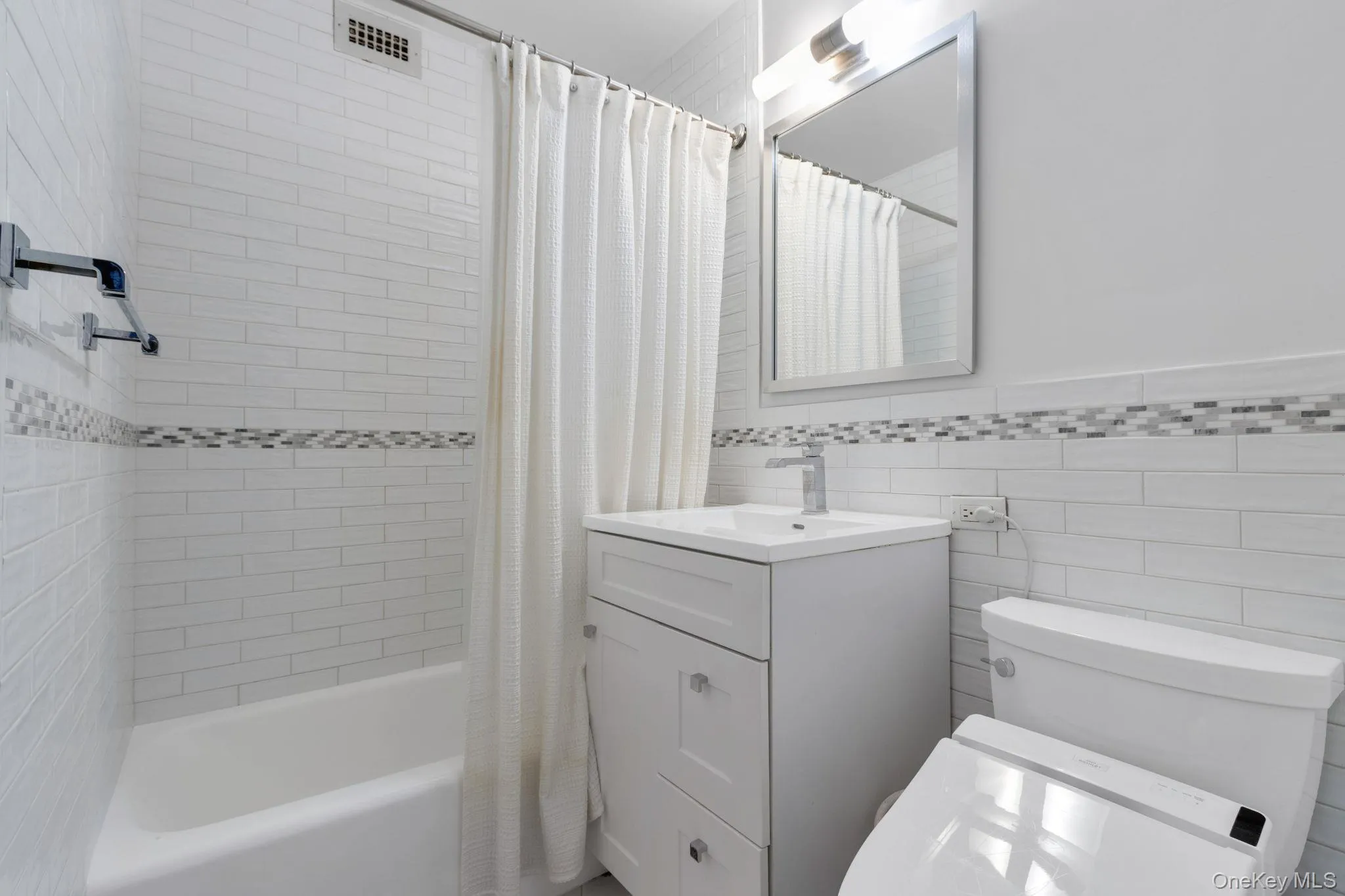 Full bath featuring shower / bath combination with curtain, vanity, and tile walls Full bath featuring shower / bath combination with curtain, vanity, and tile walls