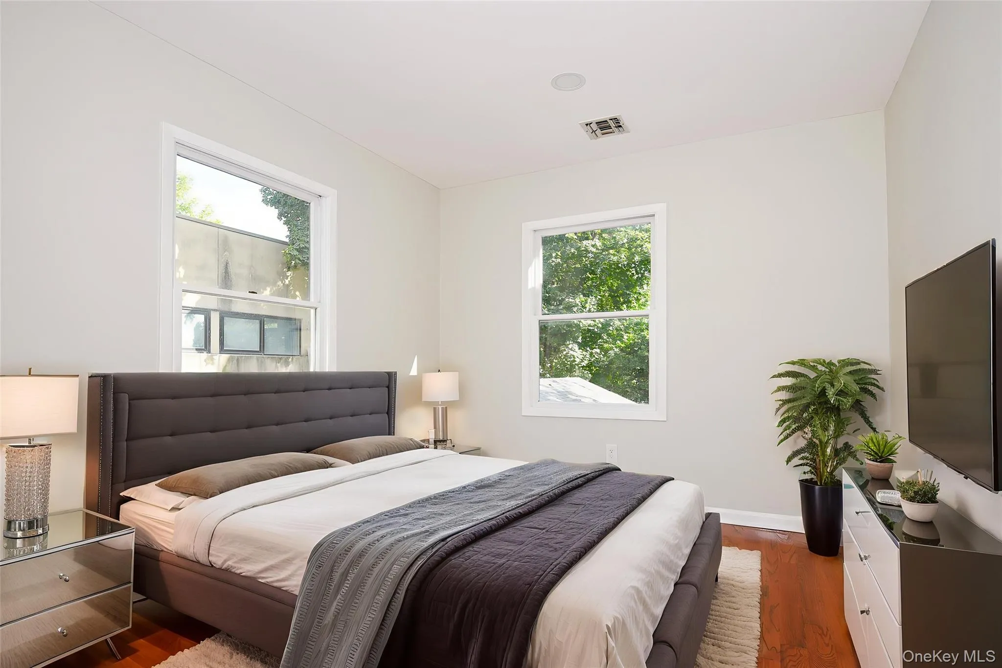 Bedroom featuring dark wood-style flooring and multiple windows Bedroom featuring dark wood-style flooring and multiple windows