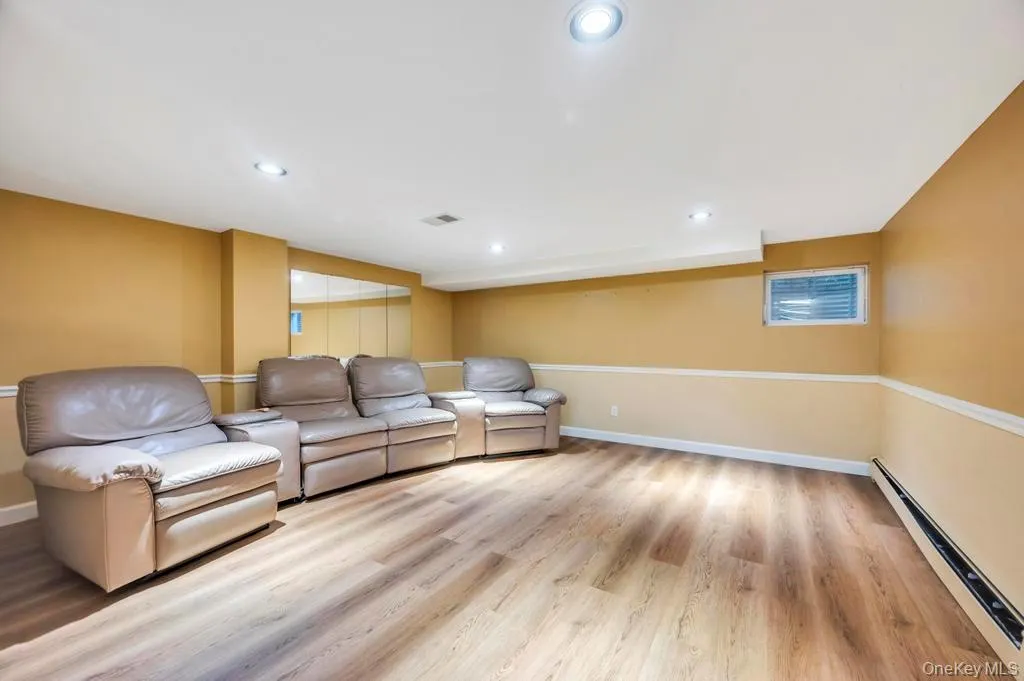 Living area featuring a baseboard radiator, light wood-type flooring, and recessed lighting Living area featuring a baseboard radiator, light wood-type flooring, and recessed lighting