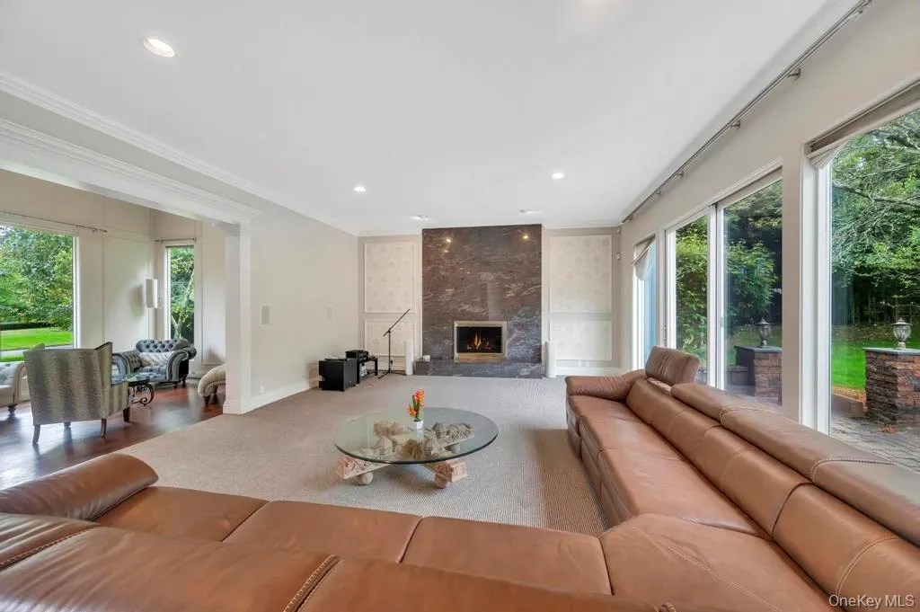 Carpeted living area featuring a fireplace, recessed lighting, and ornamental molding Carpeted living area featuring a fireplace, recessed lighting, and ornamental molding