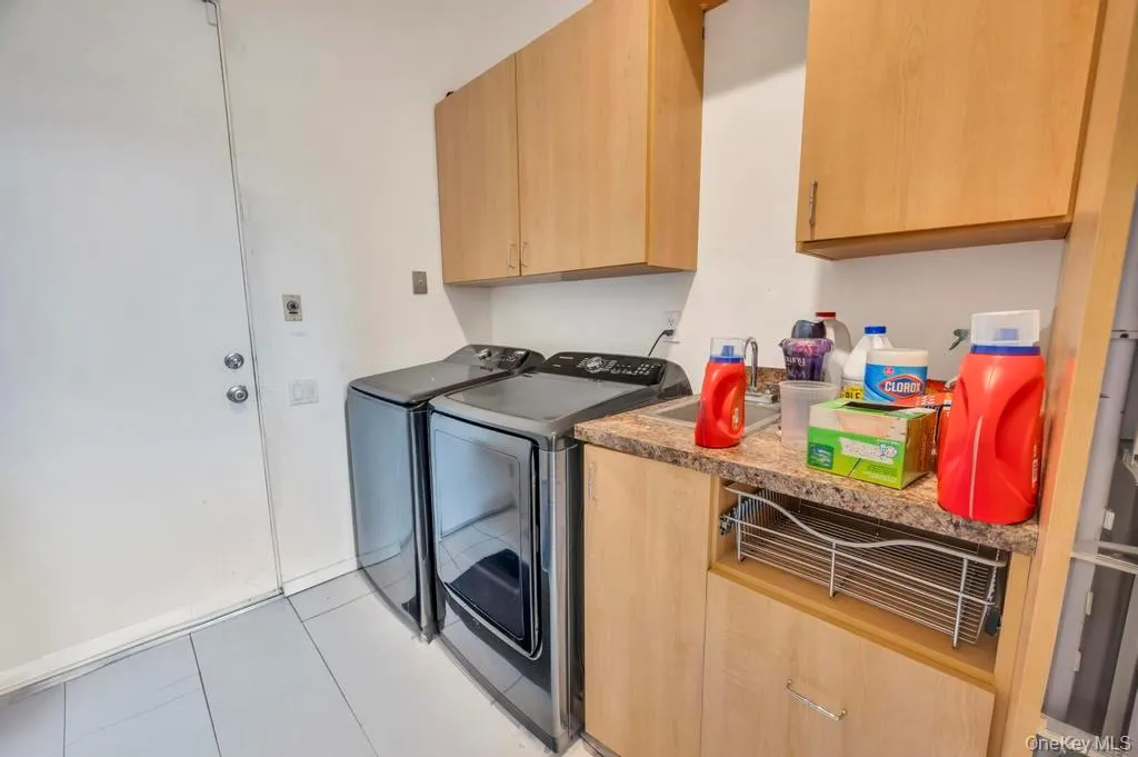Laundry room with cabinet space, light tile patterned floors, and washing machine and dryer Laundry room with cabinet space, light tile patterned floors, and washing machine and dryer