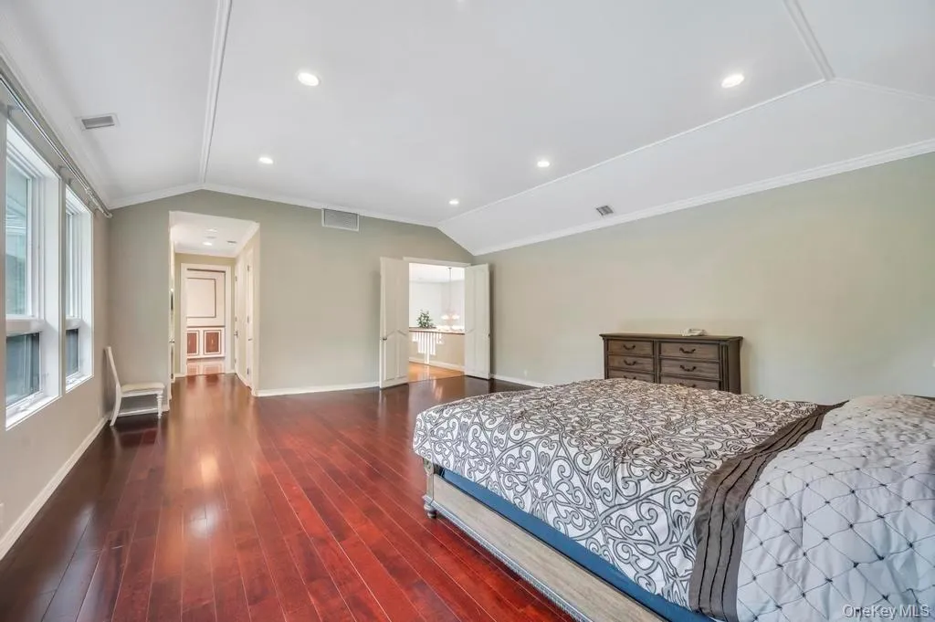 Bedroom with vaulted ceiling, ornamental molding, dark wood-style flooring, and recessed lighting Bedroom with vaulted ceiling, ornamental molding, dark wood-style flooring, and recessed lighting