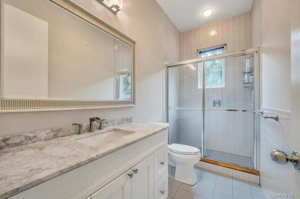 Bathroom featuring vanity, a stall shower, and light tile patterned flooring Bathroom featuring vanity, a stall shower, and light tile patterned flooring