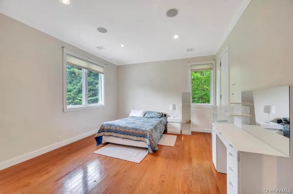 Bedroom with ornamental molding, light wood-style floors, multiple windows, and recessed lighting Bedroom with ornamental molding, light wood-style floors, multiple windows, and recessed lighting