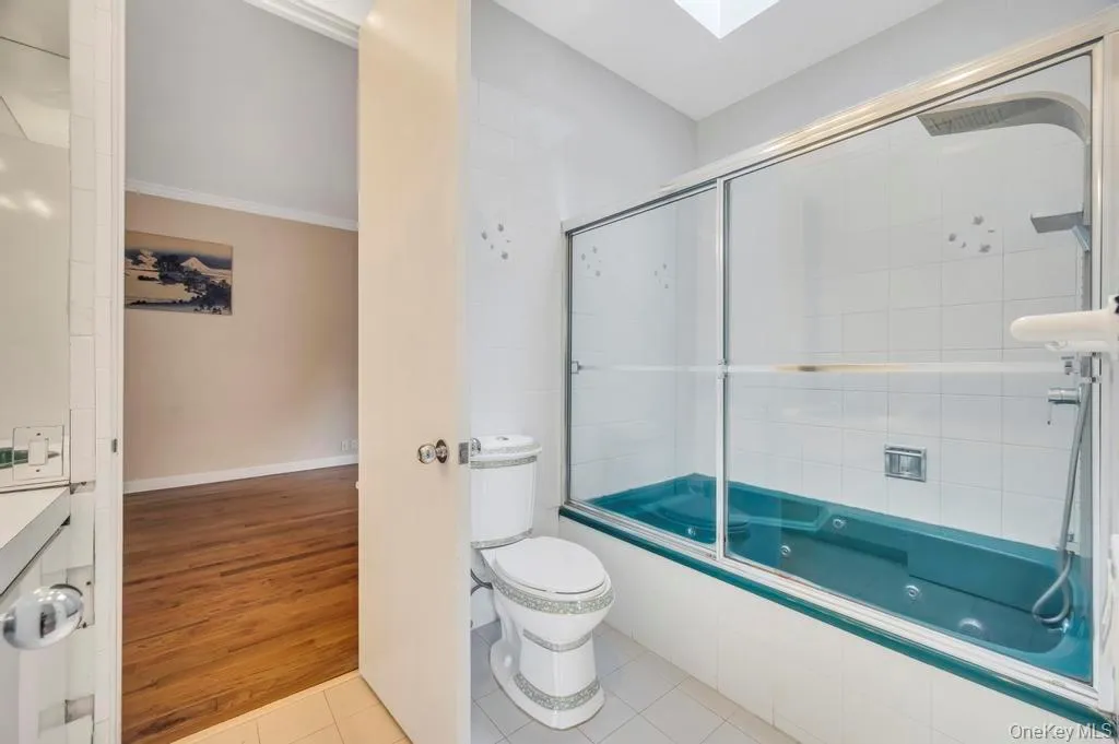 Full bathroom with light tile patterned flooring, combined bath / shower with glass door, vanity, and crown molding Full bathroom with light tile patterned flooring, combined bath / shower with glass door, vanity, and crown molding