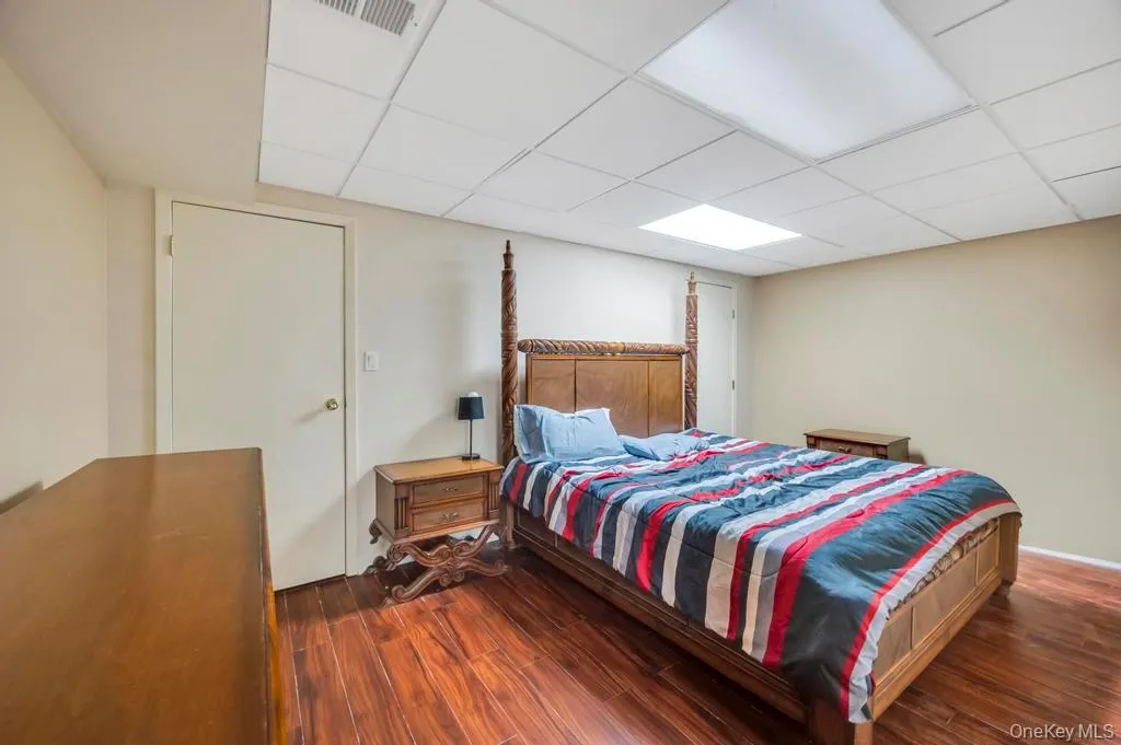 Bedroom with a drop ceiling and dark wood finished floors Bedroom with a drop ceiling and dark wood finished floors