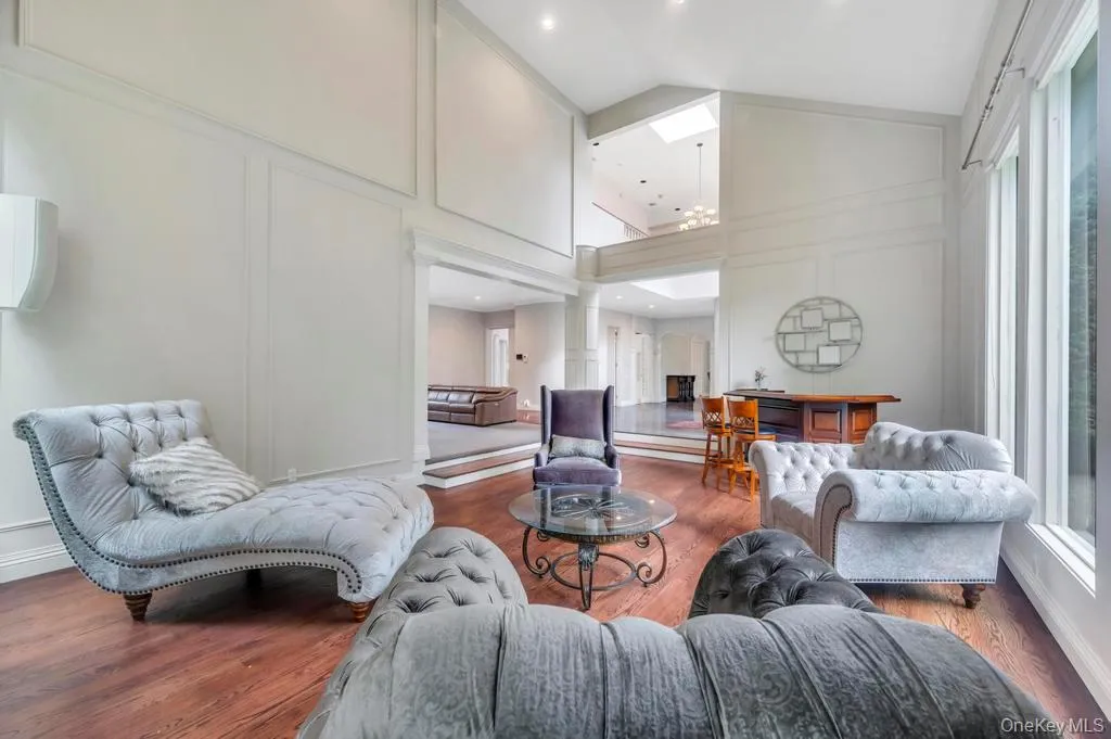 Living area featuring a decorative wall, wood finished floors, high vaulted ceiling, decorative columns, and recessed lighting Living area featuring a decorative wall, wood finished floors, high vaulted ceiling, decorative columns, and recessed lighting