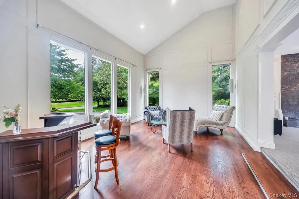 Sunroom with a decorative wall, wood finished floors, and high vaulted ceiling Sunroom with a decorative wall, wood finished floors, and high vaulted ceiling