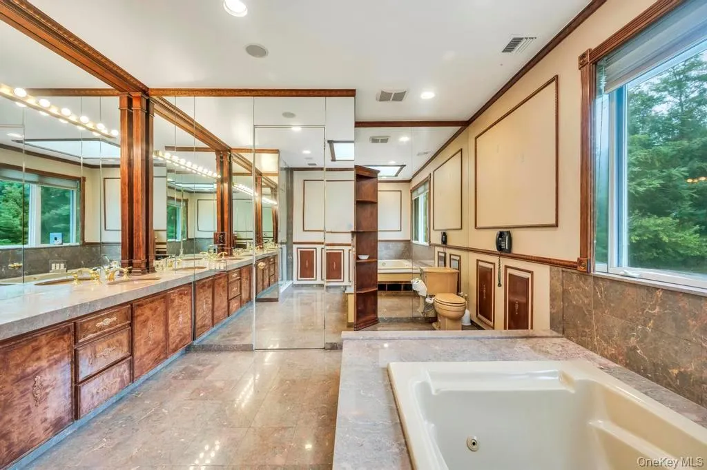 Bathroom featuring tasteful backsplash, a jetted tub, double vanity, recessed lighting, and crown molding Bathroom featuring tasteful backsplash, a jetted tub, double vanity, recessed lighting, and crown molding