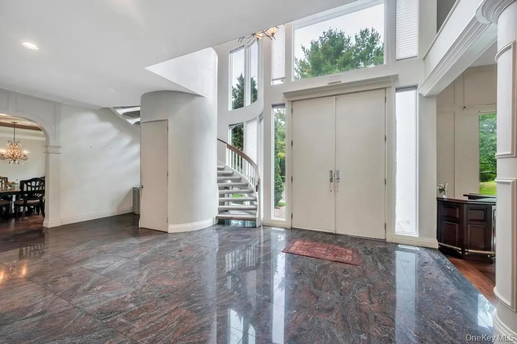Foyer entrance with arched walkways, dark marble finish floors, a chandelier, a high ceiling, and stairway Foyer entrance with arched walkways, dark marble finish floors, a chandelier, a high ceiling, and stairway