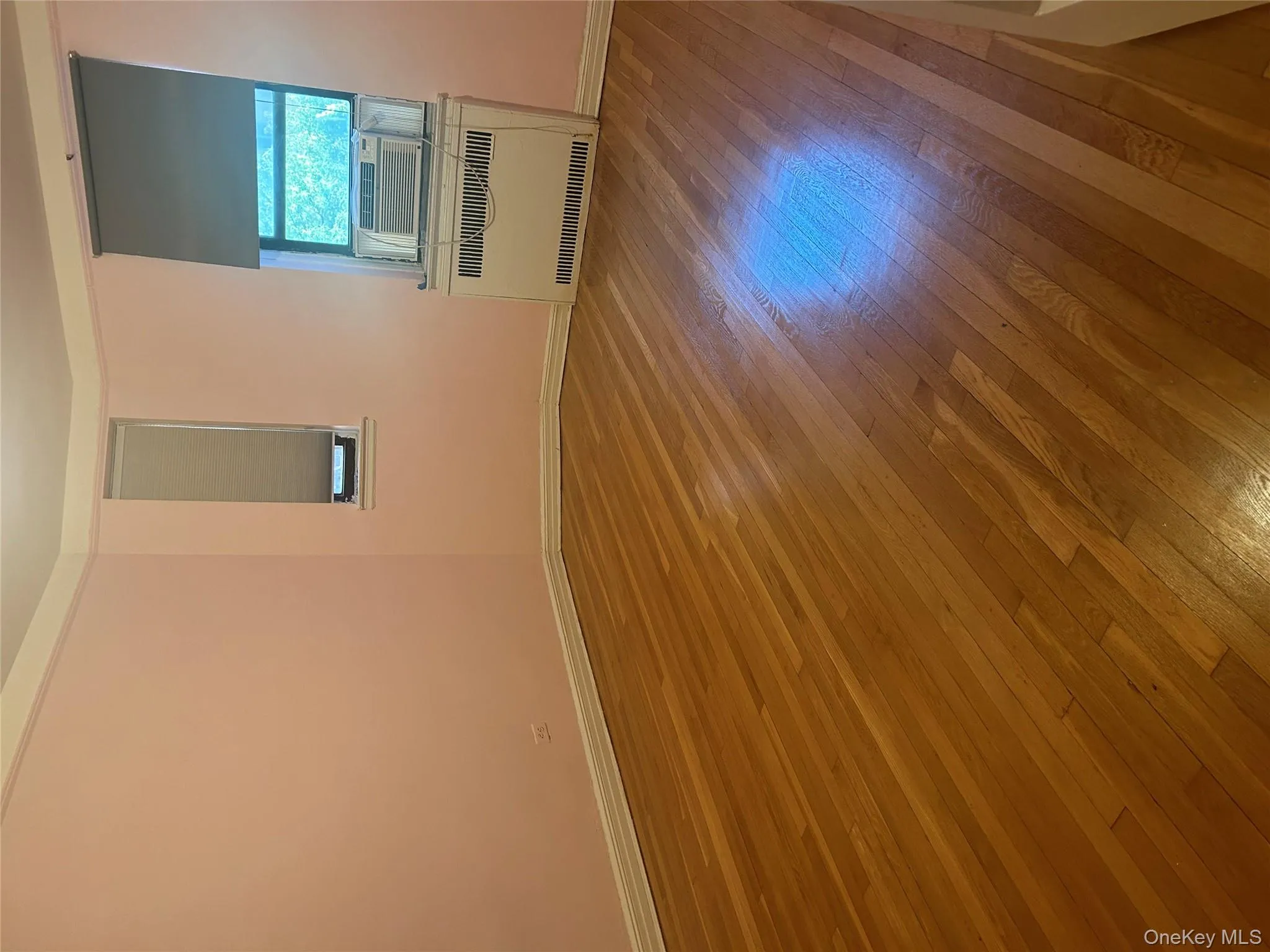 Unfurnished room featuring hardwood / wood-style flooring and heating unit Unfurnished room featuring hardwood / wood-style flooring and heating unit