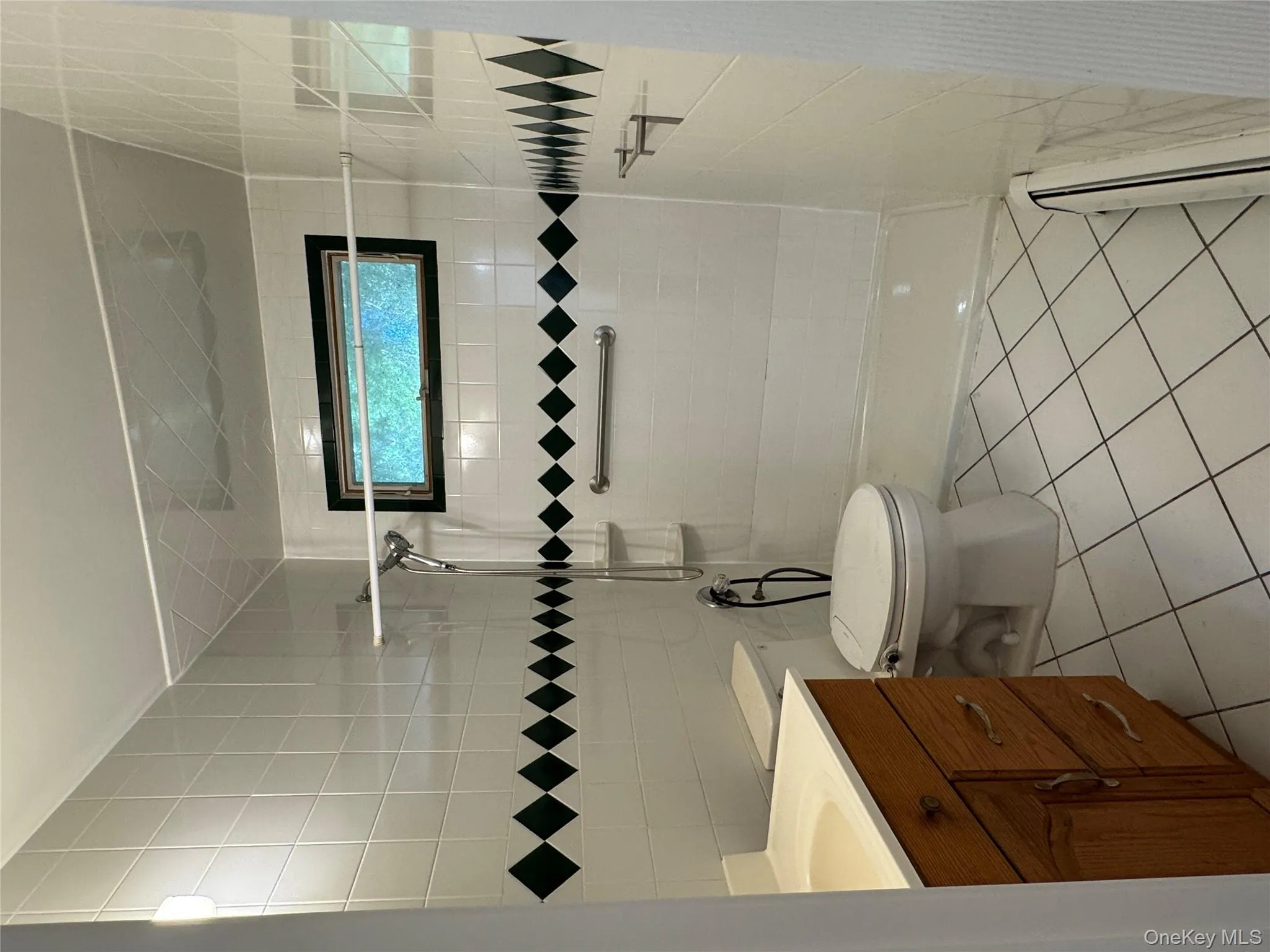 Full bath with tile walls, light tile patterned floors, vanity, a baseboard heating unit, and tiled shower Full bath with tile walls, light tile patterned floors, vanity, a baseboard heating unit, and tiled shower