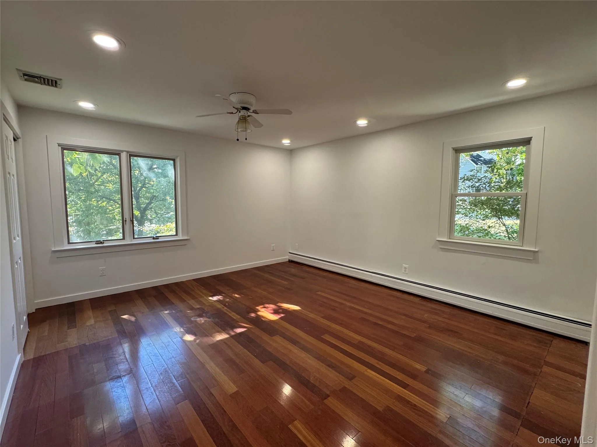 Unfurnished room with baseboard heating, dark wood-style floors, recessed lighting, and ceiling fan Unfurnished room with baseboard heating, dark wood-style floors, recessed lighting, and ceiling fan