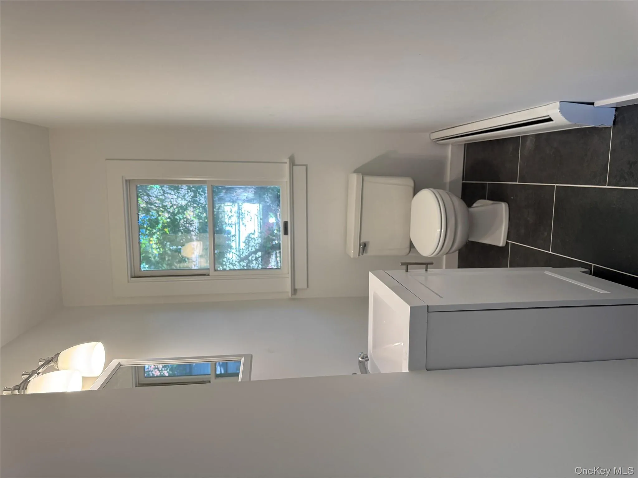 Bathroom featuring a baseboard radiator, vanity, and dark tile patterned flooring Bathroom featuring a baseboard radiator, vanity, and dark tile patterned flooring