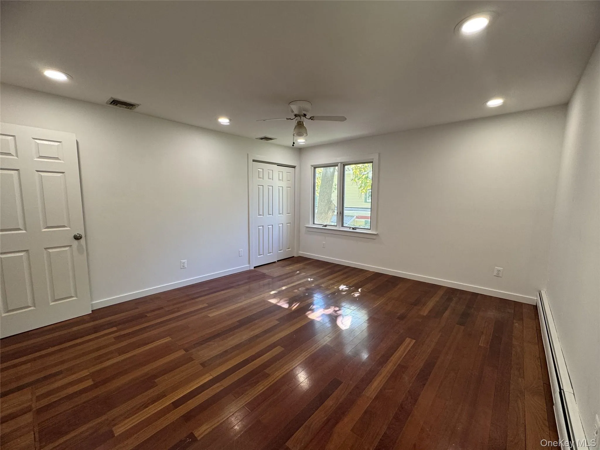 Unfurnished bedroom with baseboard heating, recessed lighting, dark wood-type flooring, ceiling fan, and a closet Unfurnished bedroom with baseboard heating, recessed lighting, dark wood-type flooring, ceiling fan, and a closet