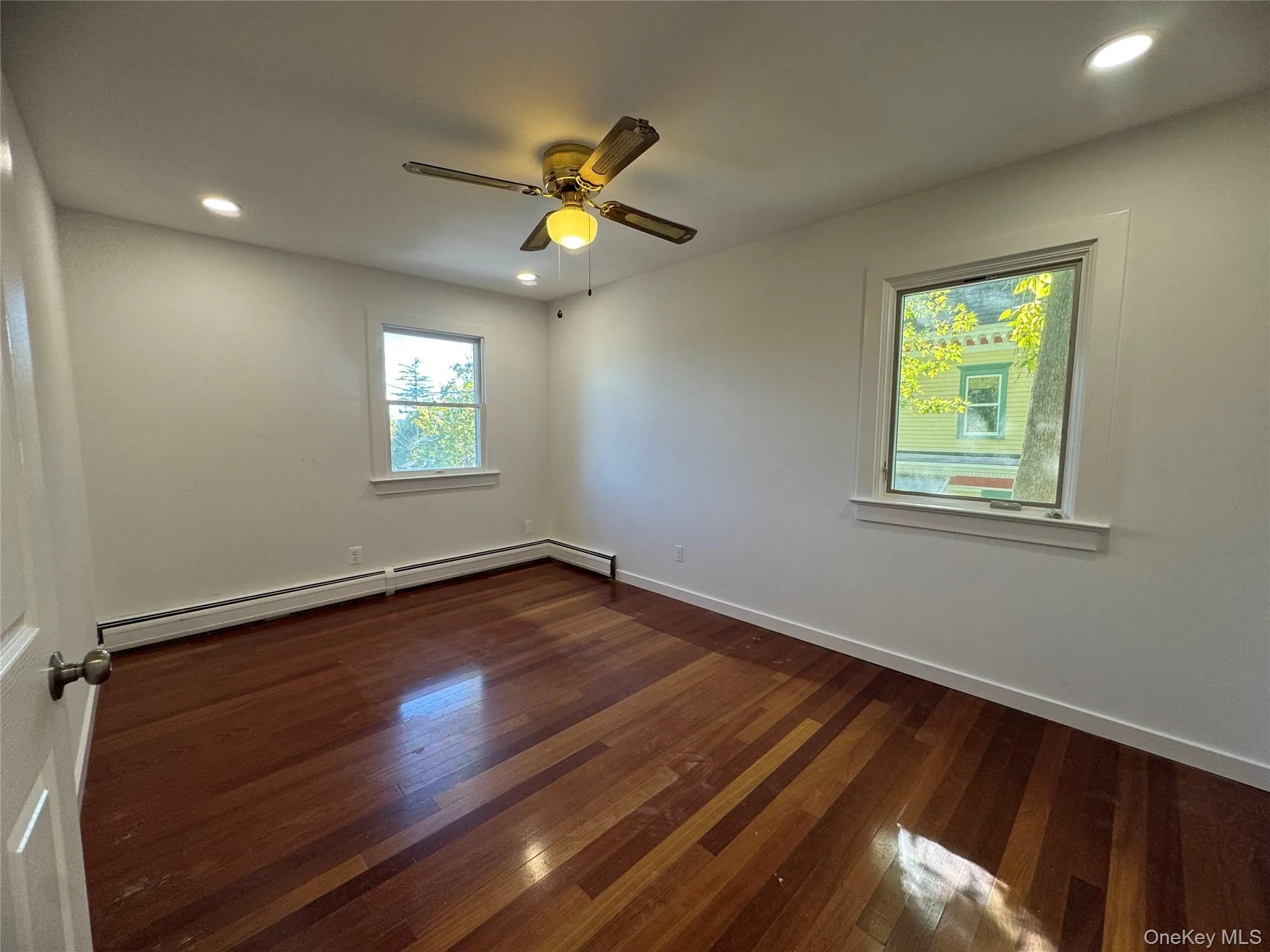 Empty room featuring recessed lighting, dark wood finished floors, a baseboard heating unit, and a ceiling fan Empty room featuring recessed lighting, dark wood finished floors, a baseboard heating unit, and a ceiling fan