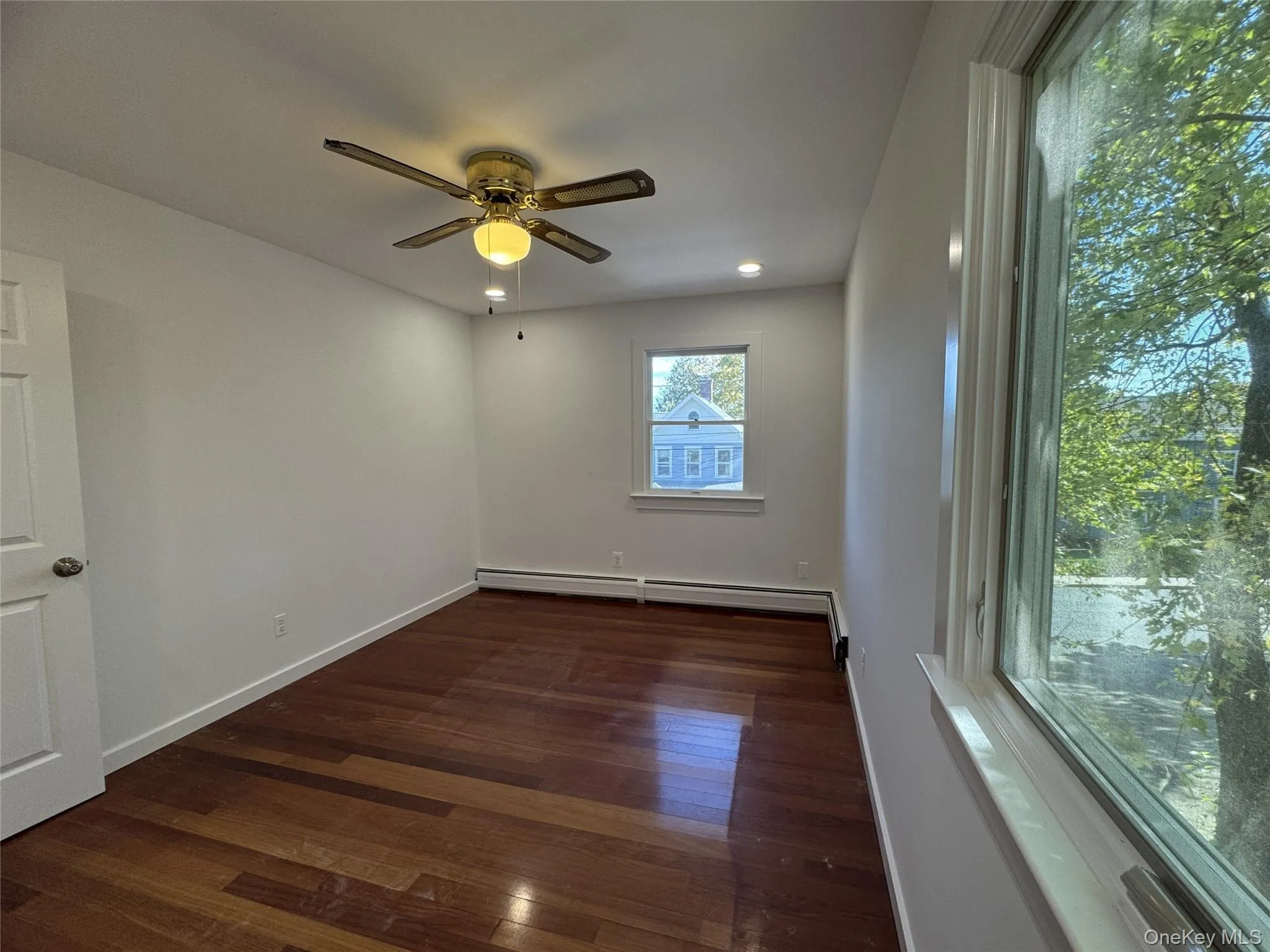 Empty room featuring dark wood finished floors, a baseboard heating unit, recessed lighting, and ceiling fan Empty room featuring dark wood finished floors, a baseboard heating unit, recessed lighting, and ceiling fan