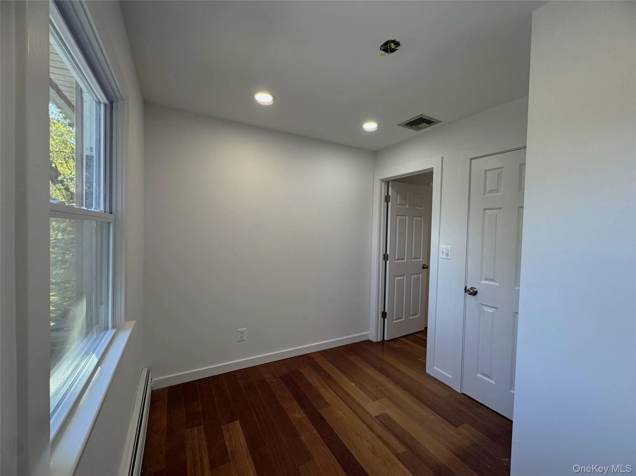 Spare room featuring dark wood-style flooring, baseboard heating, and recessed lighting Spare room featuring dark wood-style flooring, baseboard heating, and recessed lighting