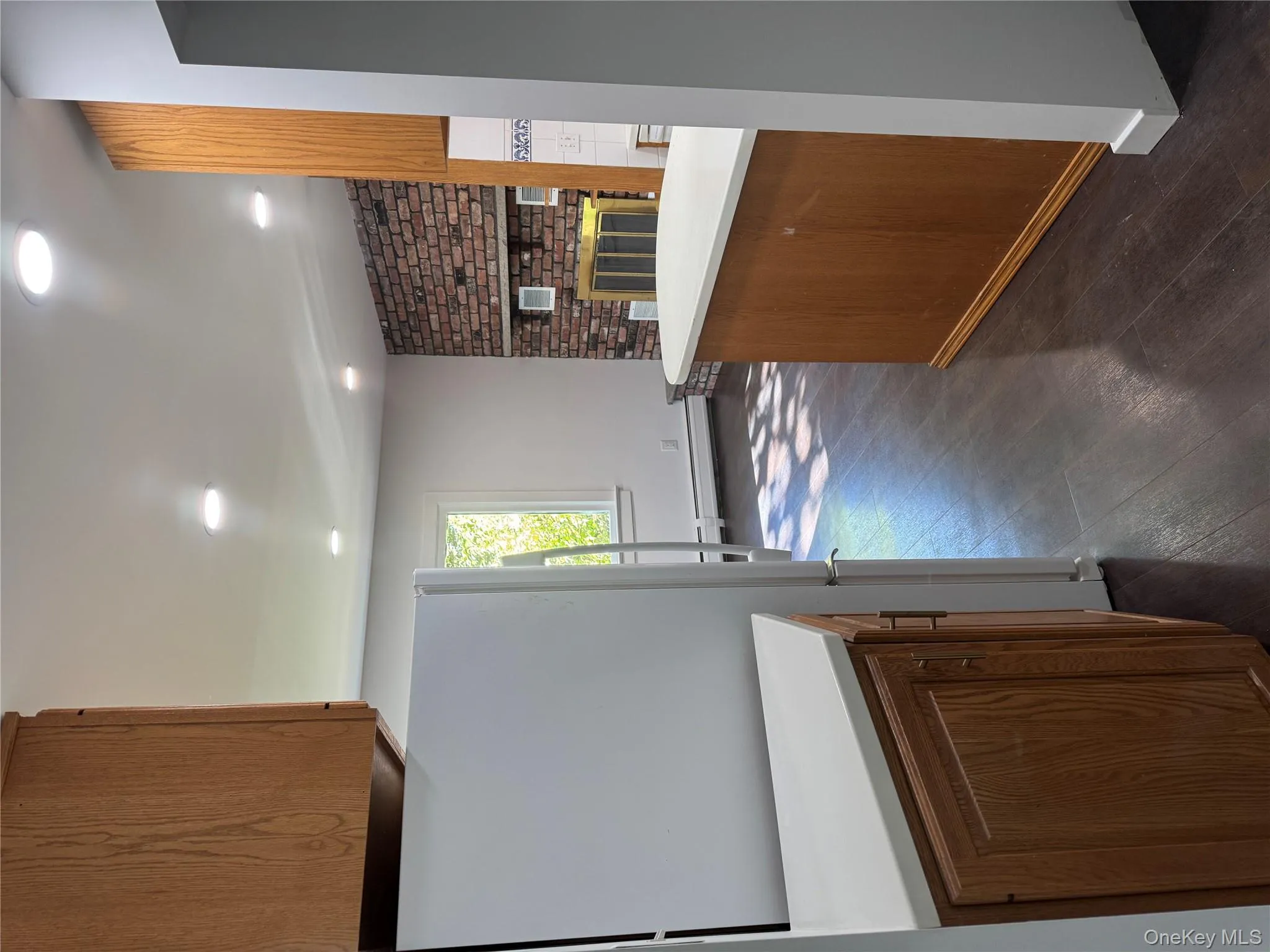 Kitchen featuring brown cabinets, light countertops, refrigerator, recessed lighting, and dark wood-type flooring Kitchen featuring brown cabinets, light countertops, refrigerator, recessed lighting, and dark wood-type flooring