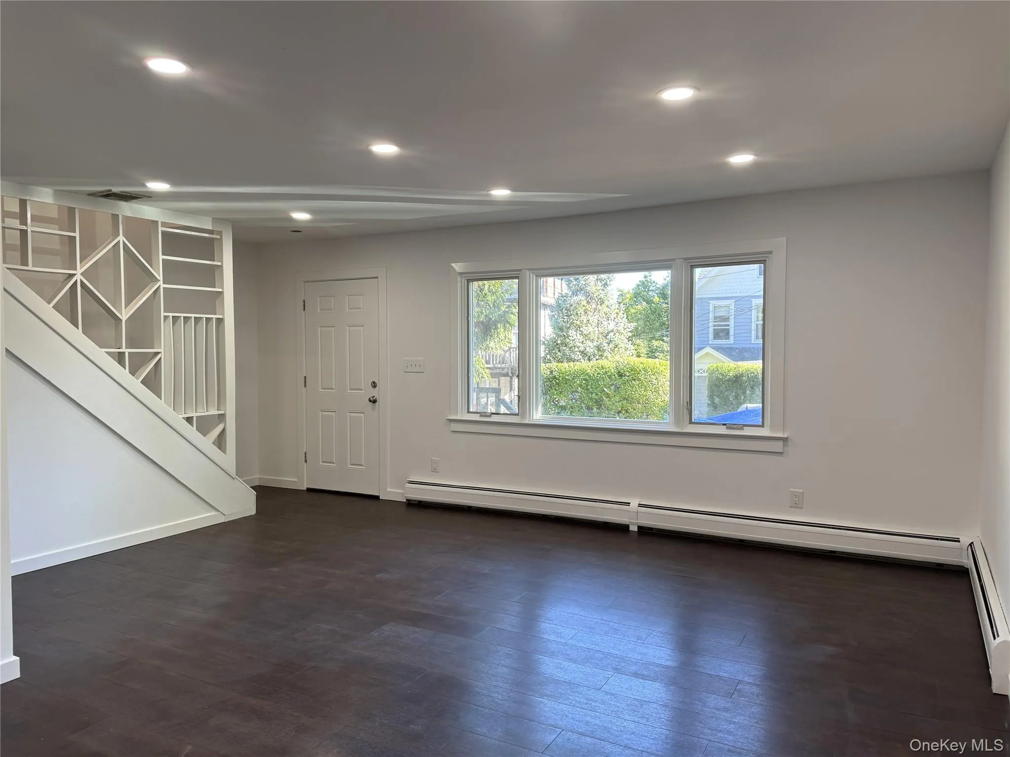 Foyer entrance featuring recessed lighting, dark wood finished floors, stairway, and a baseboard radiator Foyer entrance featuring recessed lighting, dark wood finished floors, stairway, and a baseboard radiator